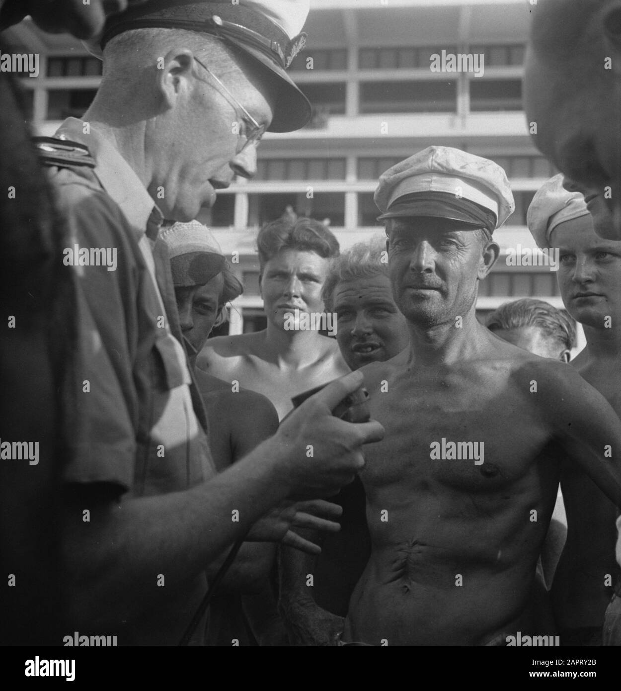 Ein Marineoffizier mit einem Mikrofon in der Hand, umgeben von Seeleuten Datum: 1947/04/01 Ort: Indonesien, Niederländische Ostindien Stockfoto