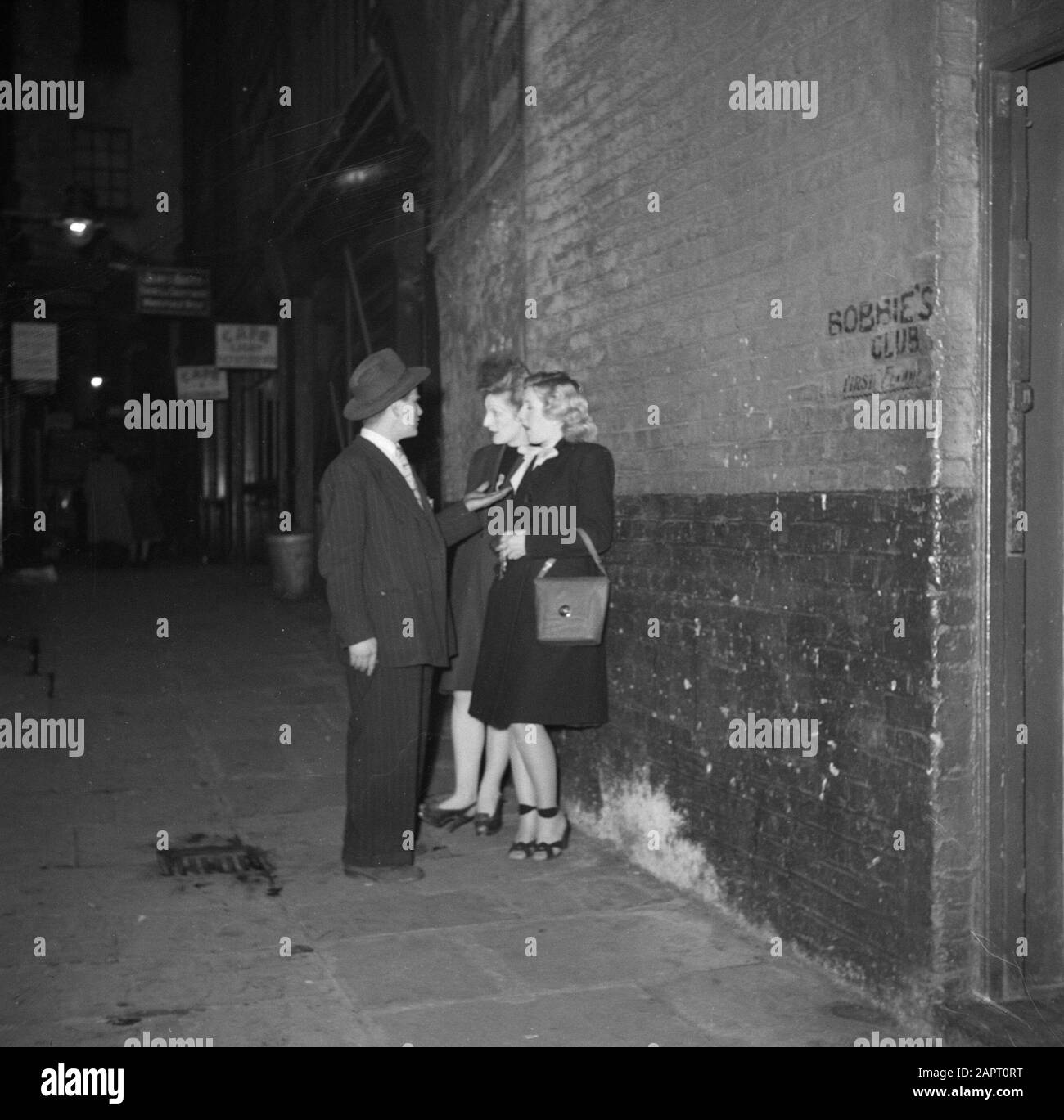 Spivs in Soho, London EIN Spiv im Gespräch mit zwei Frauen Anmerkung: Spiv ist das englische Wort für "Heiler", "Shaker" Datum: 1947 Ort: England, London Schlüsselwörter: Schwarzhandel Stockfoto