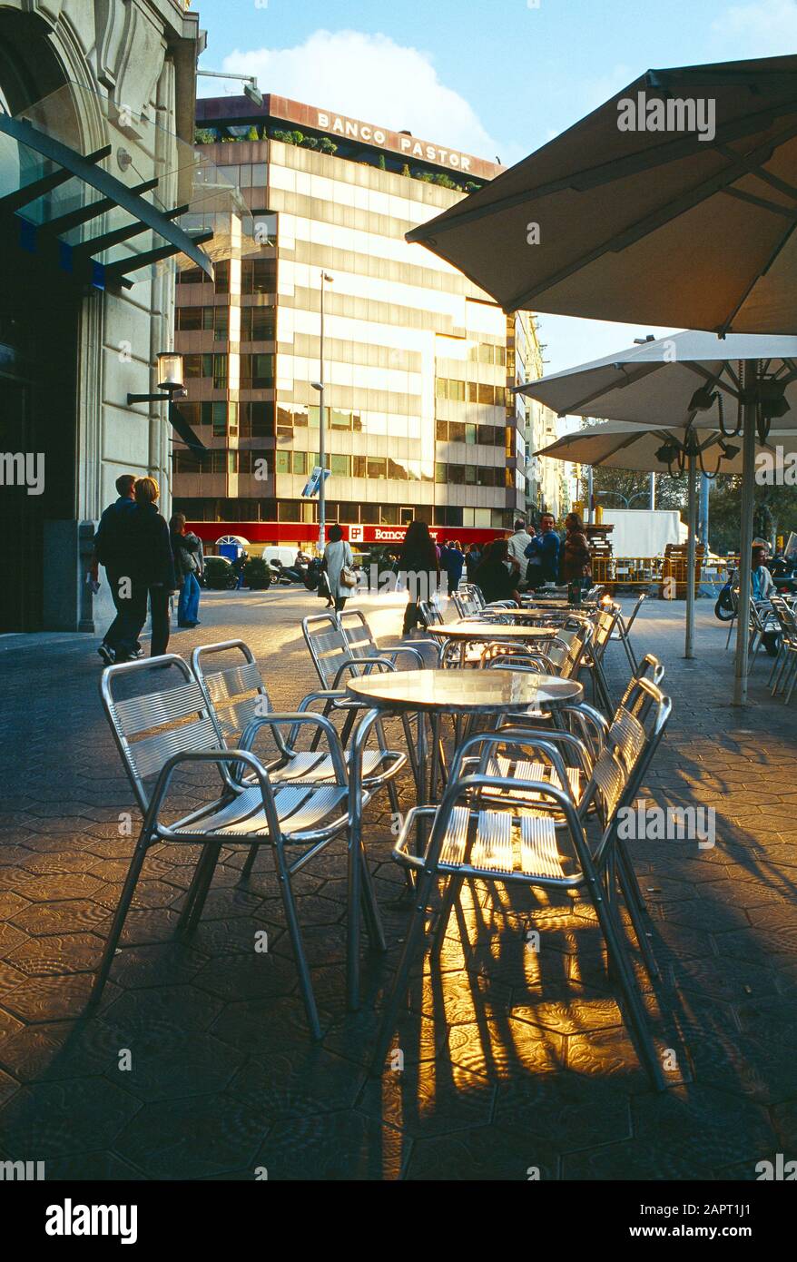 Spanien. Barcelona. Leere Stühle im Straßencafé und Blick auf das Gebäude des Banco Pastor. Stockfoto