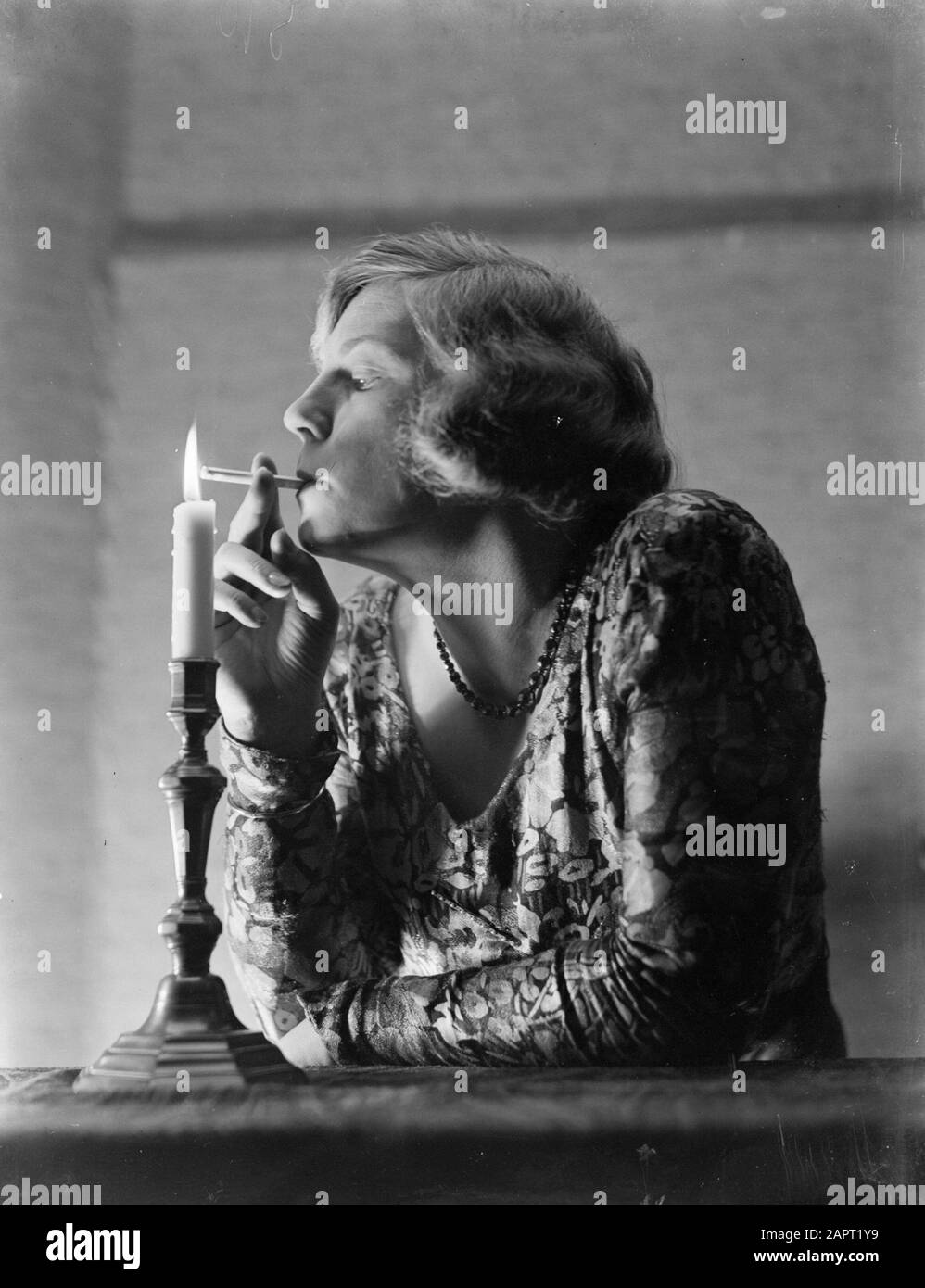 Werbefotografien EINE Frau zündet eine Zigarette an einer Kerze Datum: 1932 Schlüsselwörter: Rauchen, Zigaretten, Frauen Stockfoto