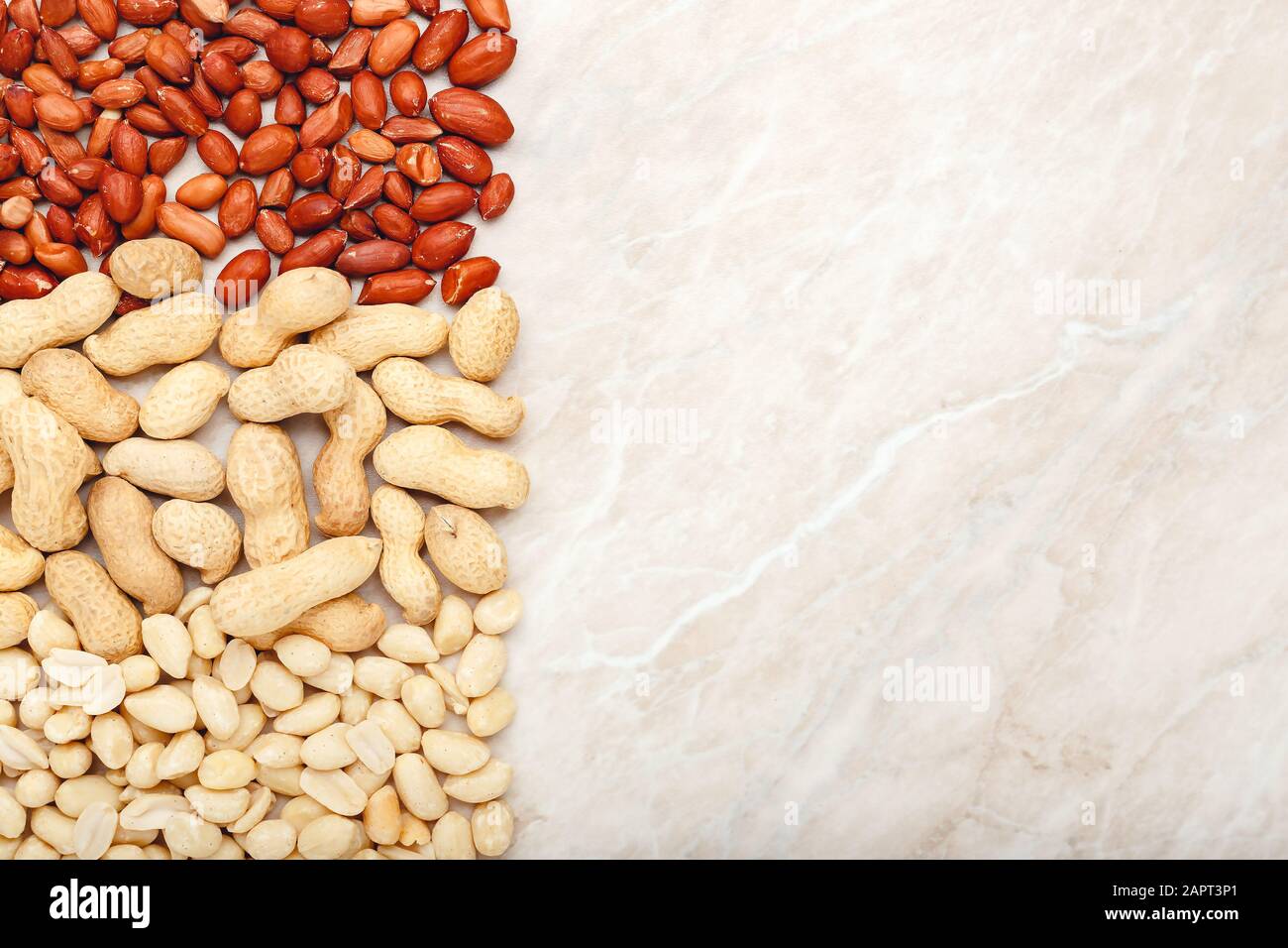 Rahmen aus MIX NUTS Erdnüssen in Schale und geschälten Erdnüssen mit Kopierraum auf weißem Marmorhintergrund. Flaches Lay mit Platz für Text, verspotst dich für dein Stockfoto