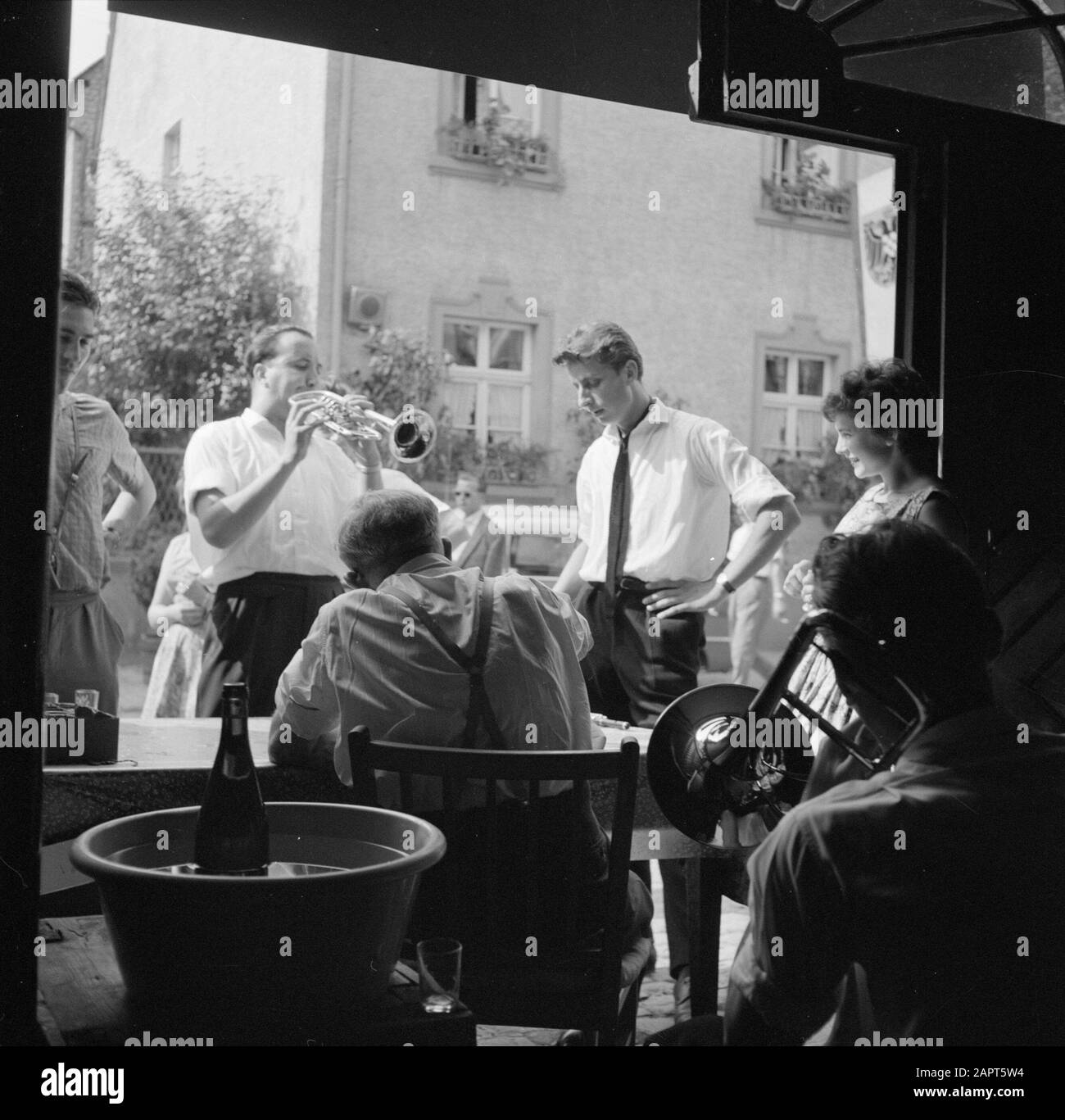 Mosel: Kostüm- und Weinfest Partygänger und Musiker am Eingang einer Winzerfirma Datum: 4. Juli 1959 Ort: Deutschland, Kröv, Rheinland-Pfalz, Westdeutschland Schlagwörter: Blasinstrumente, Musiker, Publikum, Volksfeste, Wein, Weinkeller Stockfoto