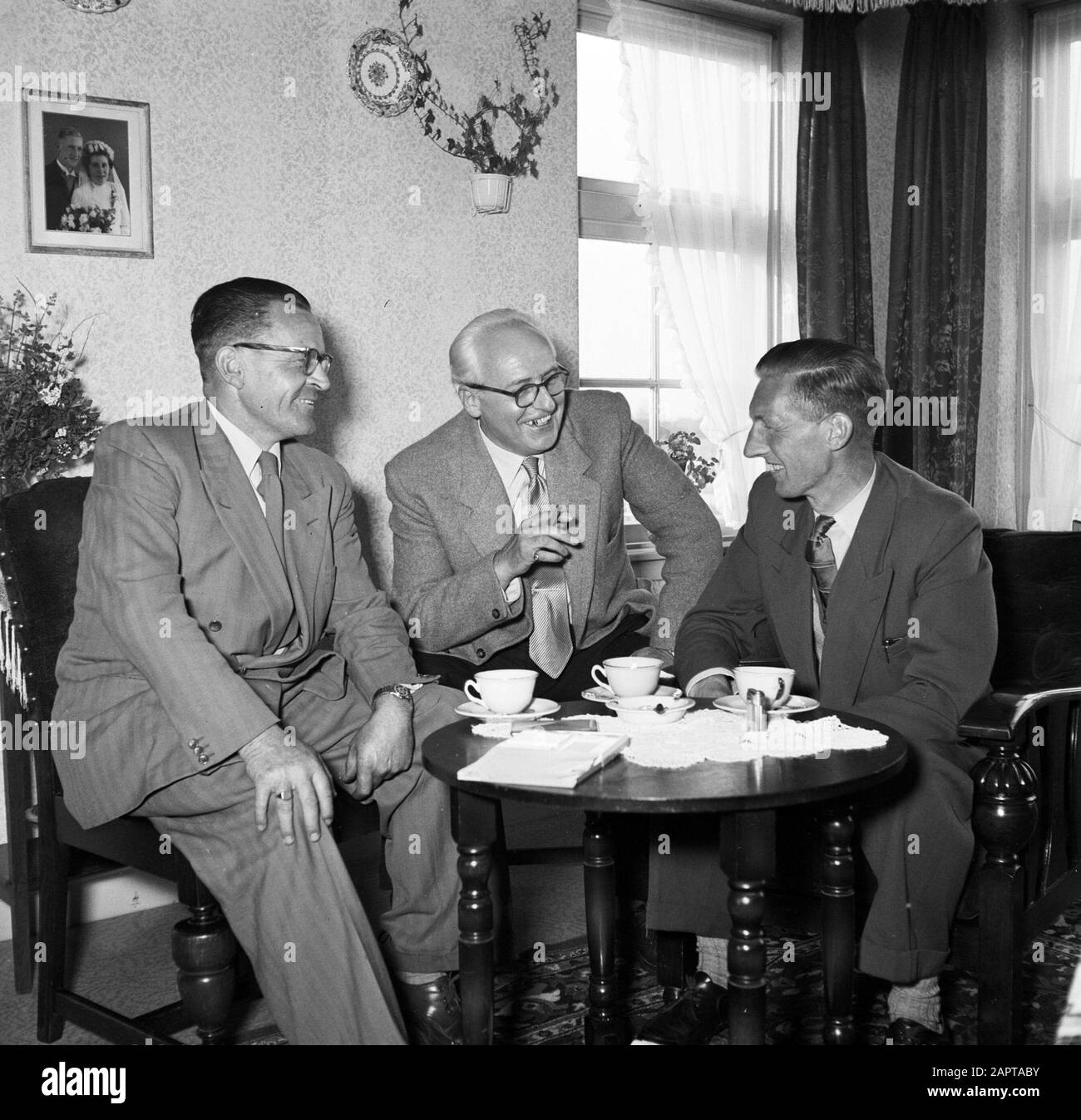 Gerard de Jong im Gespräch mit Ynse Postma und dem Fotografen Willem van de Poll. An der Wand ein Hochzeitsfoto des Ehepaares De Jong Annotation: Gerard de Jong überlebte am 7. April 1945 um Dronrijp eine Fusillade. Ynse Postma leistete De Jong erste Hilfe und half mit seinem Transport zu einem sicheren Haus Datum: 1955-00-01 Ort: Friesland, Leeuwarden Schlüsselwörter: Erste Hilfe, Besucher, Fotos, Gespräche, Hilfe, Ehen, Innenräume, Möbel, Menschen in Verstecken, Geschirr, Eigenheime Personenname: Jong, Gerard de, Poll, Willem van de, Postma, Ynse Stockfoto