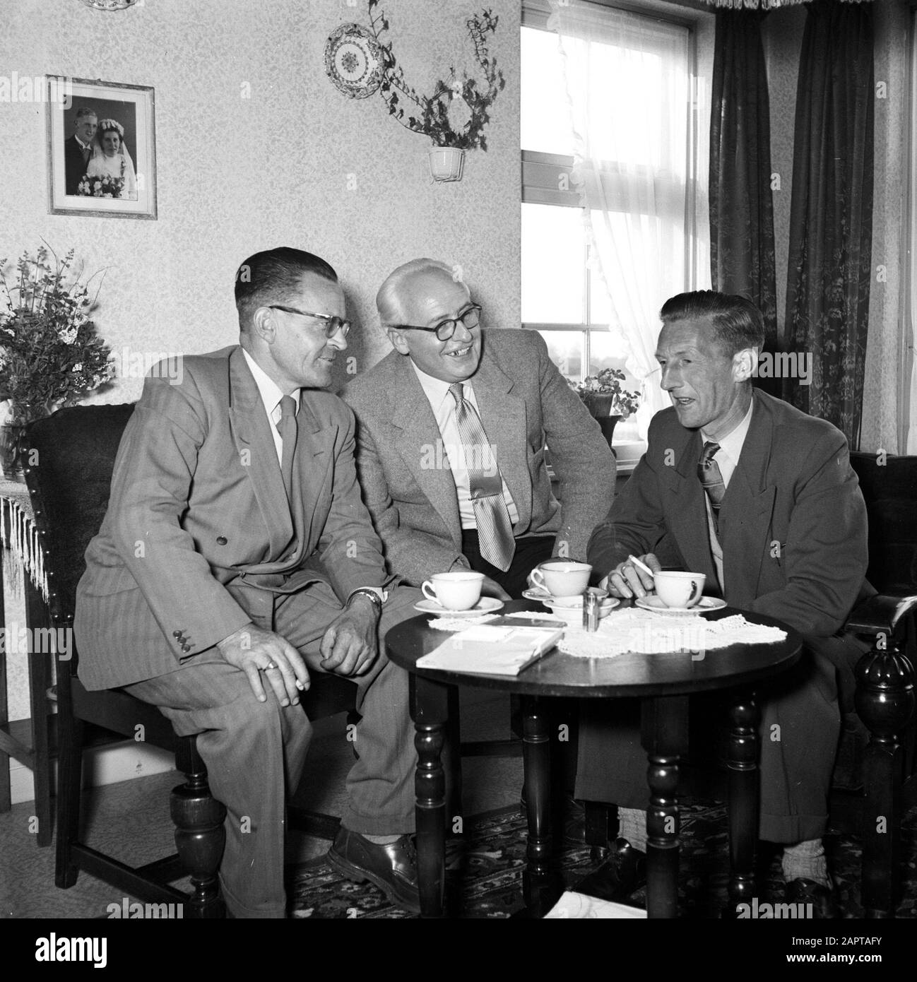 Gerard de Jong im Gespräch mit Ynse Postma und dem Fotografen Willem van de Poll. An der Wand ein Hochzeitsfoto des Ehepaares De Jong Annotation: Gerard de Jong (rechts im Bild) war der einzige, der am 7. April 1945 in der Nähe von Dronrijp eine Fusillade überlebte. Ynse Postma leistete De Jong erste Hilfe und half mit seinem Transport zu einem sicheren Haus Datum: 1955-00-01 Ort: Friesland, Leeuwarden Schlüsselwörter: Erste Hilfe, Besucher, Fotos, Gespräche, Hilfe, Ehen, Innenräume, Möbel, Menschen in Verstecken, Geschirr, Eigenheime Personenname: Jong, Gerard de, Poll, Willem van de, Postma, Ynse Stockfoto