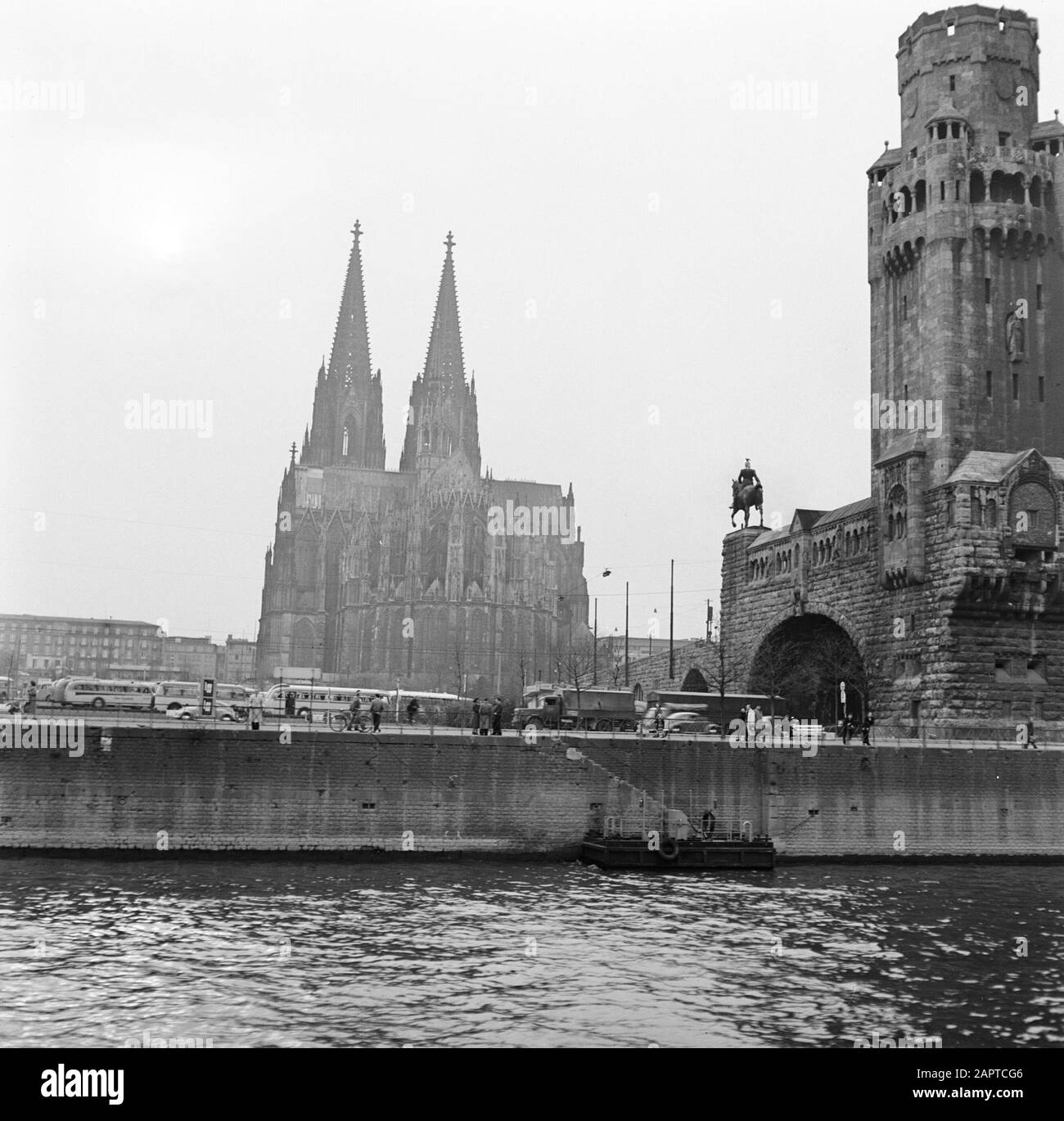 Rheinnavigation, Bericht vom Schlepper Damco 9: Westdeutschlandblick Köln vom Rhein, mit dem Dom und rechts einer der Eingangstürme der hohenernbrücke Datum: 1. april 1955 Standort: Deutschland, Köln, Westdeutschland Schlagwörter: Busse, Kirchenbauten, Flüsse, Eisenbahnbrücken, Stadtplastiken, Statuen, Lastwagen Stockfoto