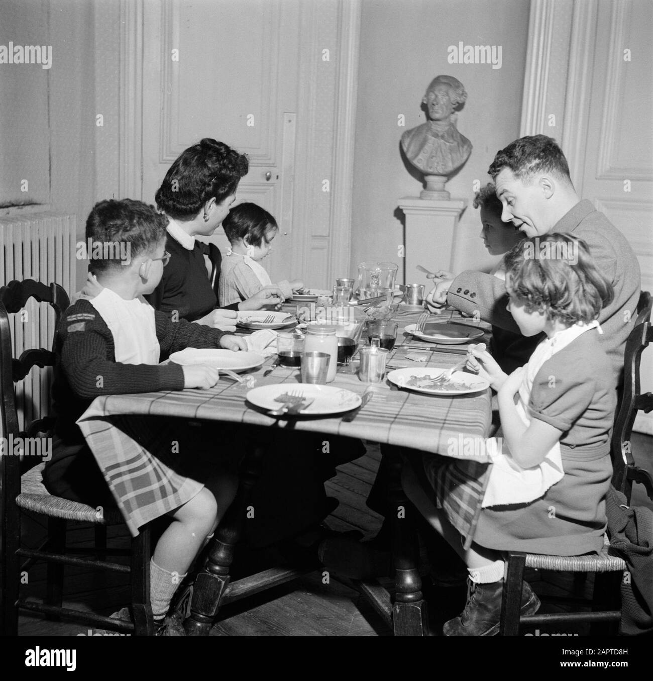 Bewohner eines Apartmentgebäudes in Paris Familie am Tisch während des Essens Datum: 1950 Ort: Frankreich, Paris Schlüsselwörter: Skulpturen, Familien, Kinder, Mahlzeiten, Geschirr Stockfoto