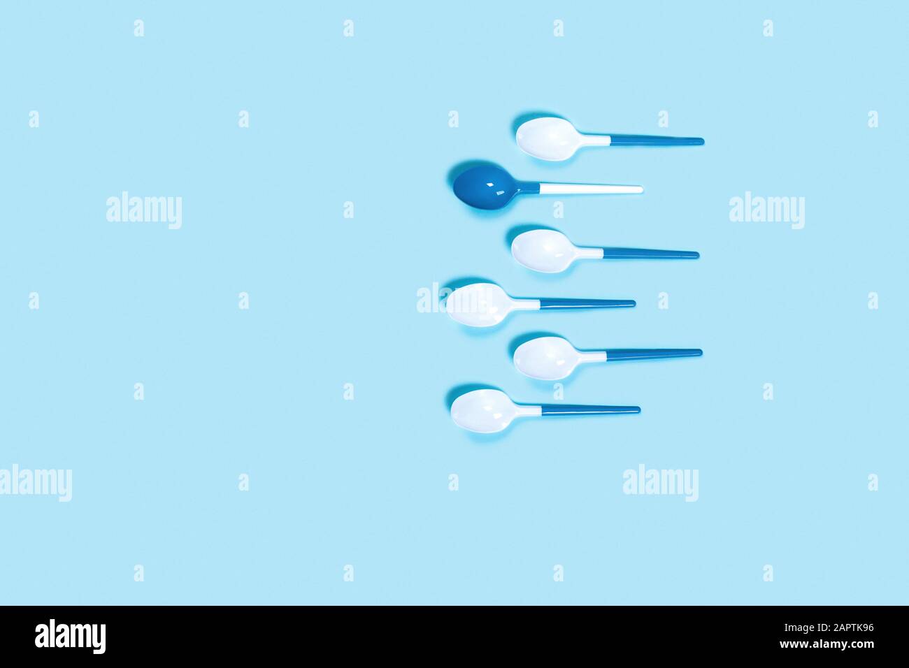 Muster aus weißem Kunststoff Löffel auf blauem Hintergrund. Vertikale Bild. Flach, Ansicht von oben. Stockfoto