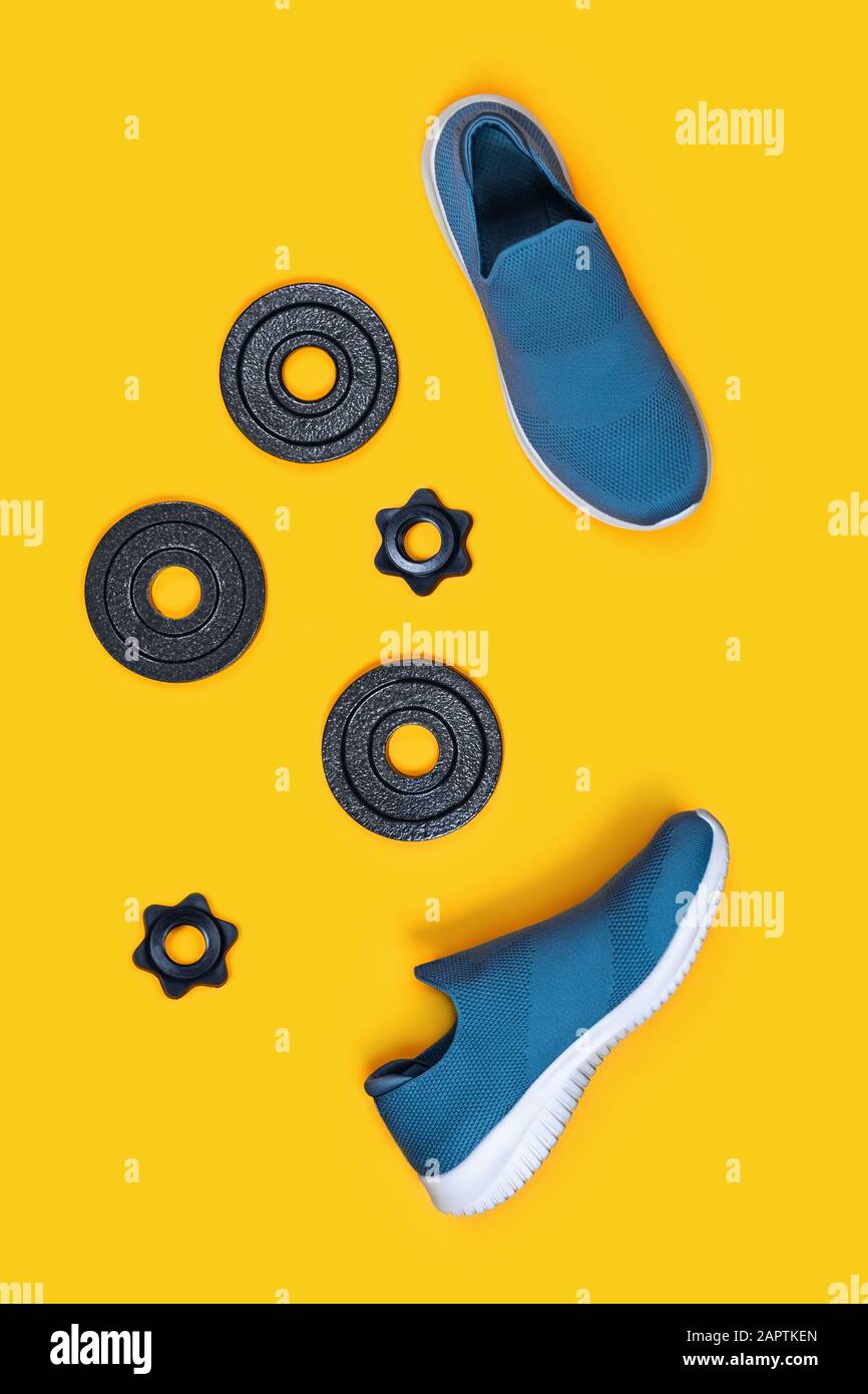 Vertikaler Hintergrund für Sport. Hanteln und Turnschuhe auf gelbem Hintergrund. Flaches Layout, Draufsicht, Kopierbereich. Stockfoto