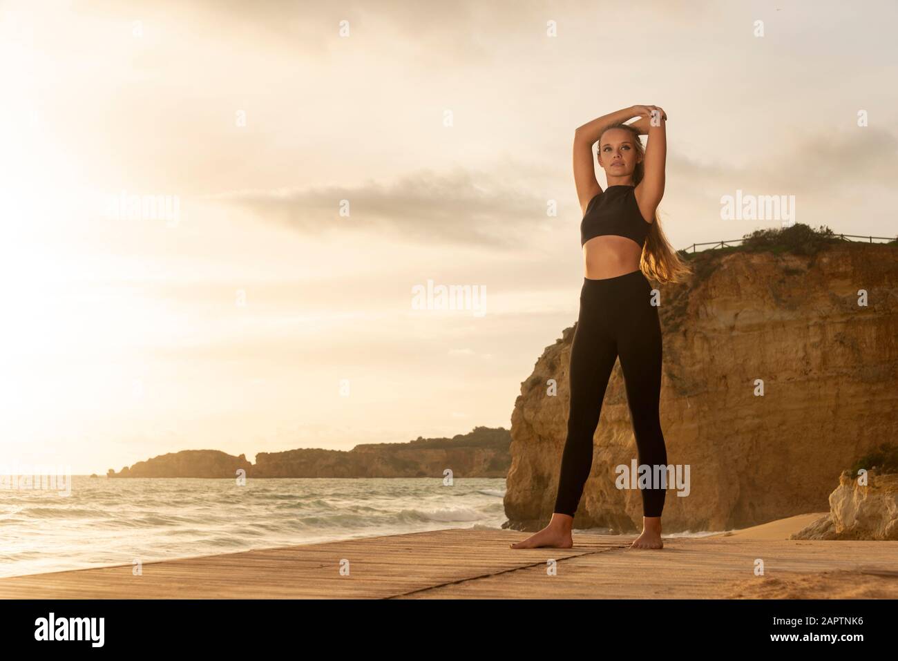 Fit Frau trägt Sportswear Stretching, Aufwärmübungen am Strand. Stockfoto