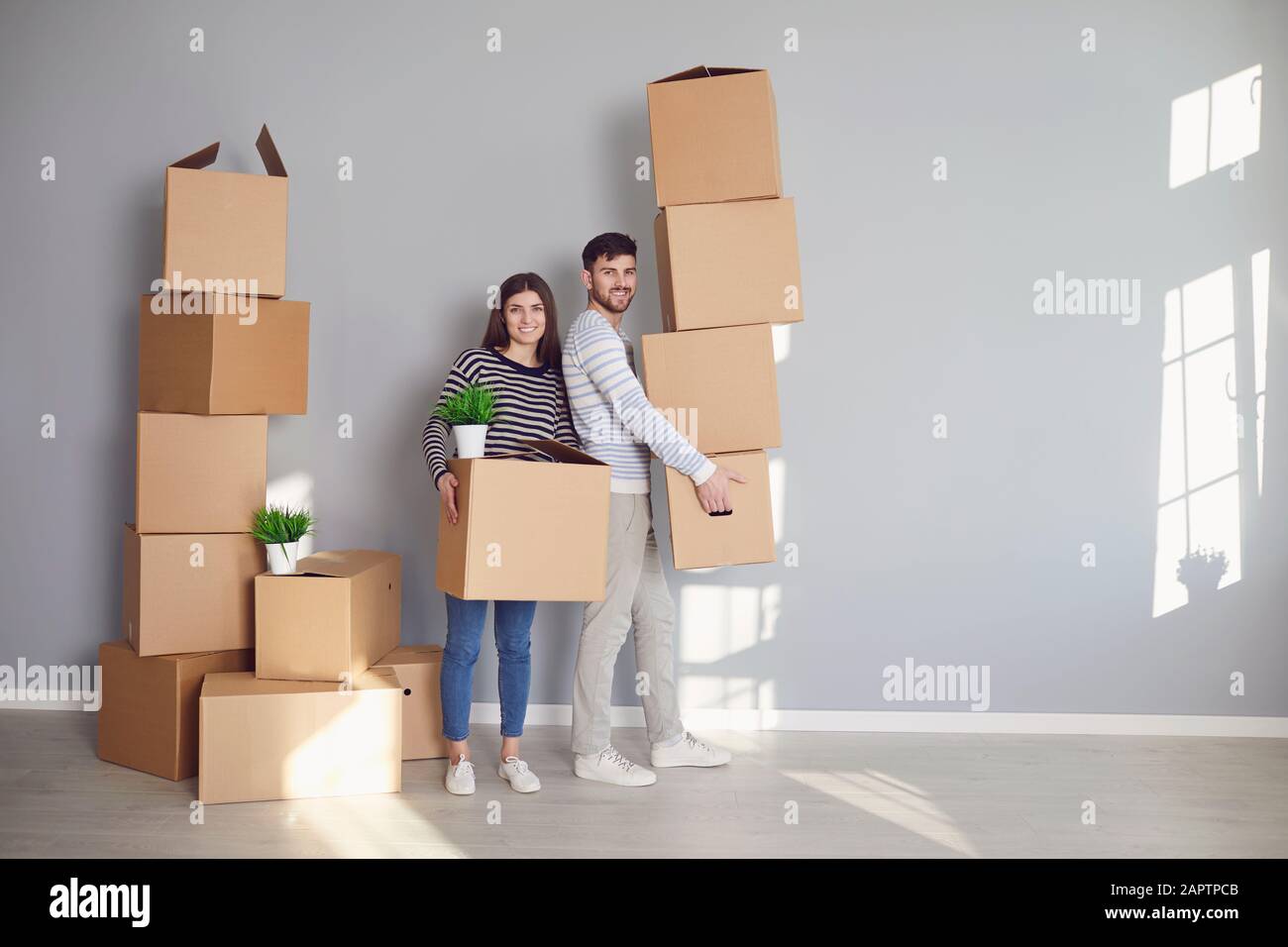 Junge Paar-Familie mit Kisten, die in einem neuen Hausraum umziehen sollen. Stockfoto
