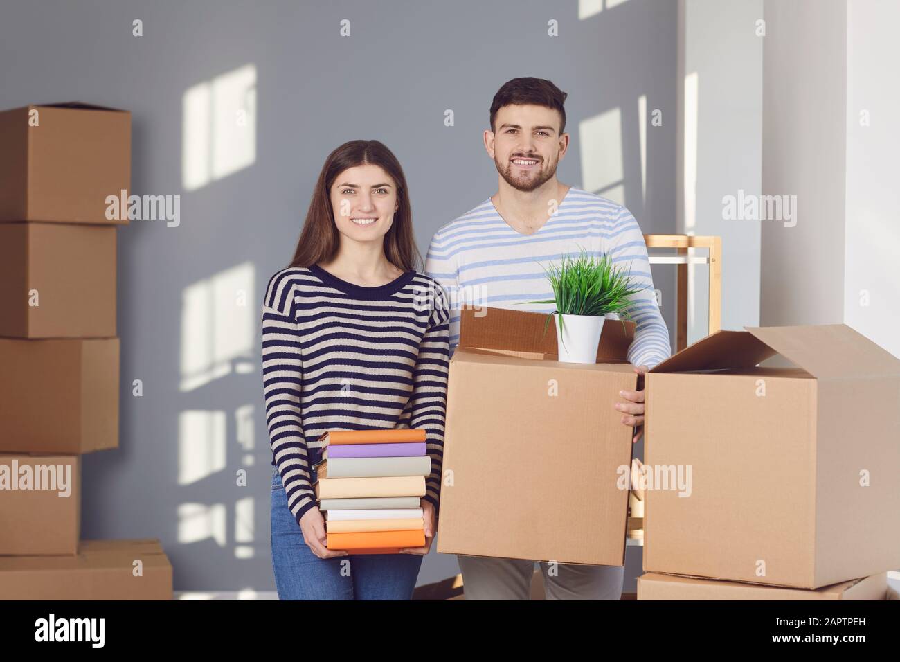 Junge Paar-Familie mit Kisten, die in einem neuen Hausraum umziehen sollen. Stockfoto