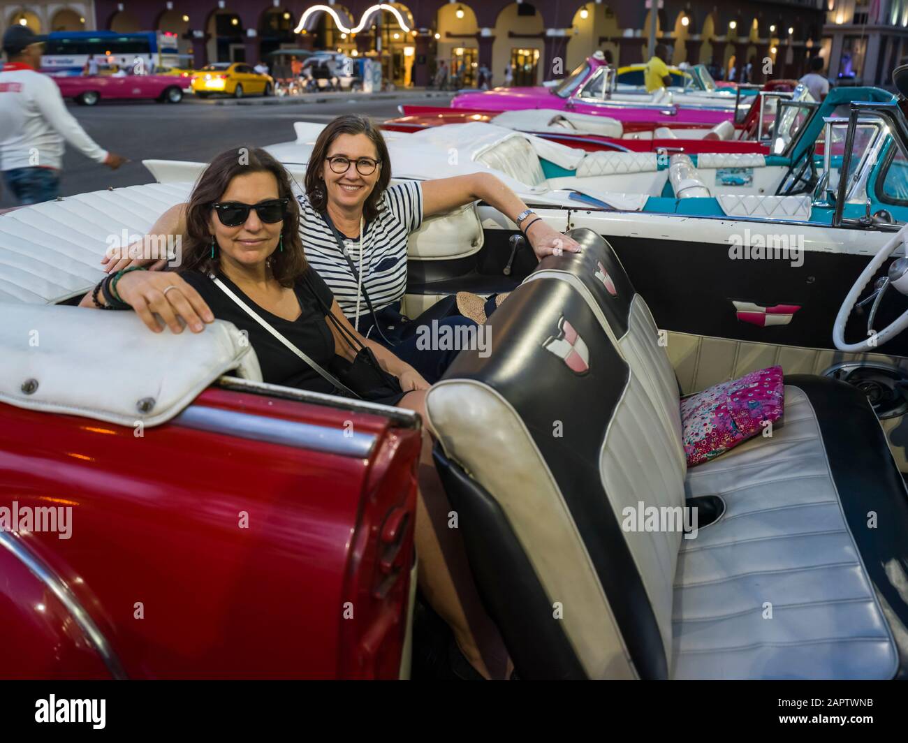Zwei Frauen sitzen auf dem Rücksitz eines Oldtimers und schauen auf die Kamera; Havanna, Kuba Stockfoto