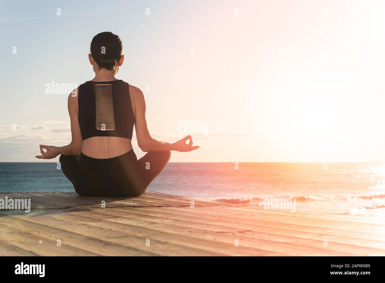 Junge Frau, die Yoga in der Nähe des Meeres praktiziert. Harmonielehre und Meditationskonzept. Gesunder Lebensstil Stockfoto