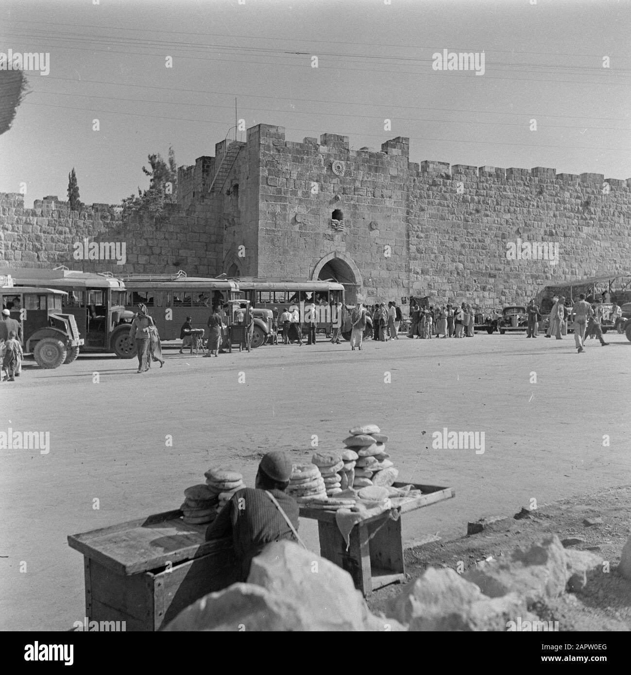 Israel 1948-1949 Jerusalem. Blick auf das Herodes Gate mit Bussen, Autos und Öffentlichkeit mit einem Brothändler im Vordergrund Datum: 1948 Ort: Israel, Jerusalem Schlüsselwörter: Architektur, Autos, Busse, Brot, Stadtstatuen, Stadtmauern, Stadttore, Straßenhändler, Verkehrsmittel Personenname: Herodes the Great (König) Stockfoto