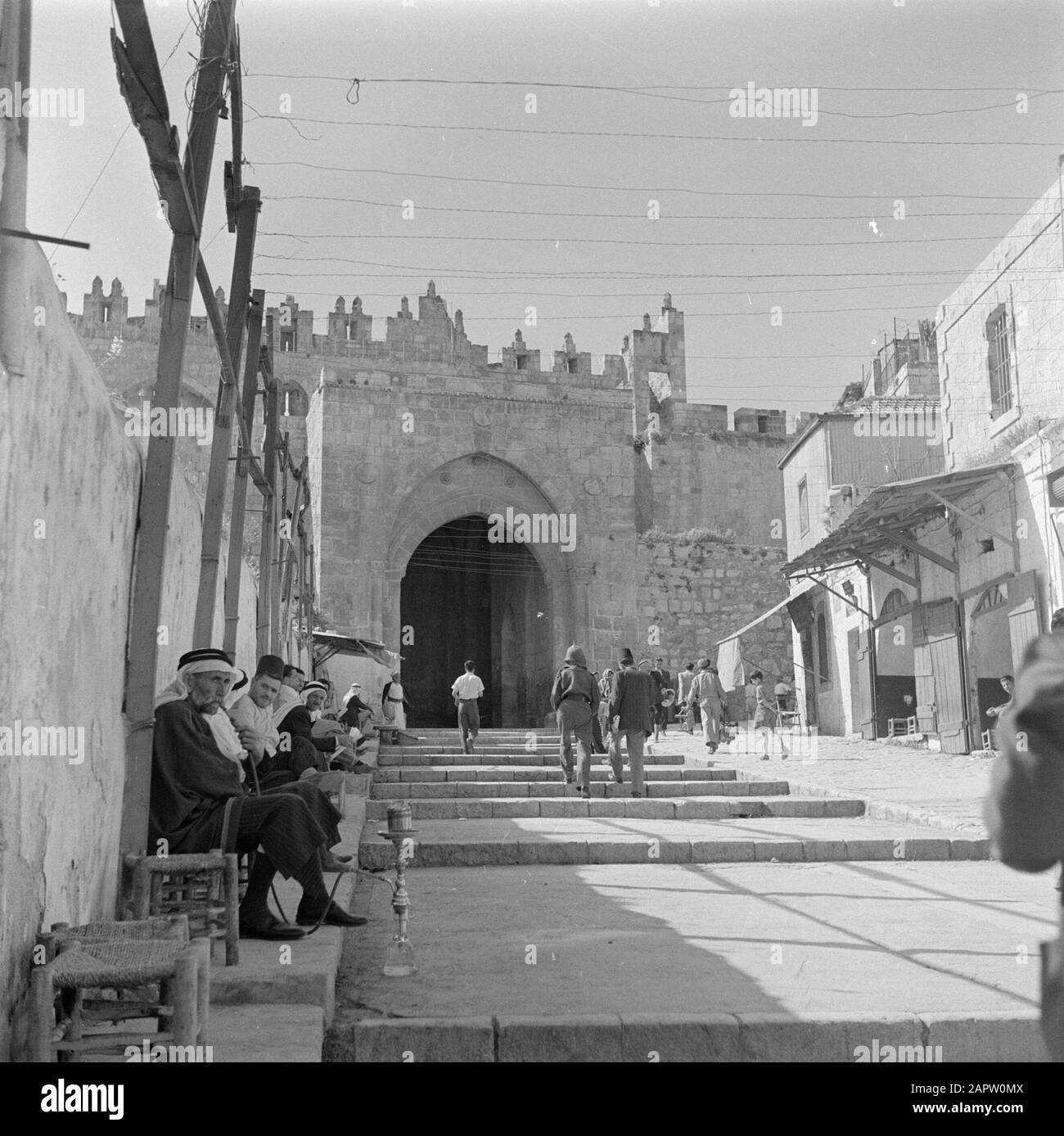 Israel 1948-1949 Jerusalem, Damaszener Tor mit Geschäften und Öffentlichkeit. Rechts ein Mann mit einer Wasserleitung und mitten auf der Straße ein jordanischer Polizist mit seinem typischen Helmdatum: 1948 Ort: Damaskus, Israel, Jerusalem Schlüsselwörter: Architektur, Polizei, Öffentlichkeit, Stadtstatuen, Stadtmauern, Stadttore, Treppen, Hookahs, Geschäfte Stockfoto