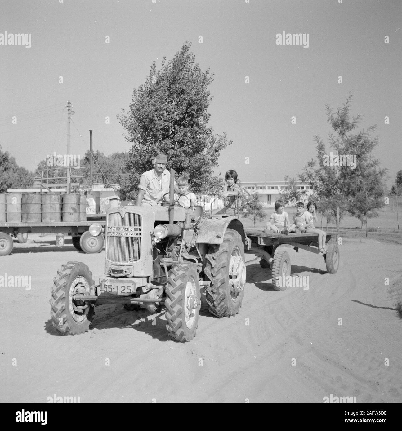 Israel - Nir Elyahu Kibbutz Nir Elyahu. Ein Erwachsener Kibbutz-Einwohner mit Kindern auf einem Traktor mit Luftreifenwagen Datum: 1. Januar 1963 Standort: Israel, Nir Elyahu Schlüsselwörter: Kibbutz, Kinder, Traktoren Stockfoto