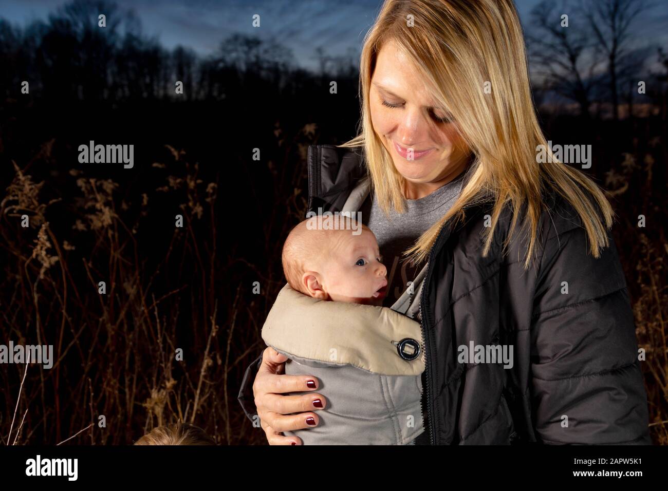 Einzelne kaukasische Mut-Wanderungen Mit Ihrem Neugeborenen Kind, Das An seinem Brustkorb An EINEM modrigen Herbsttag Befestigt ist Stockfoto