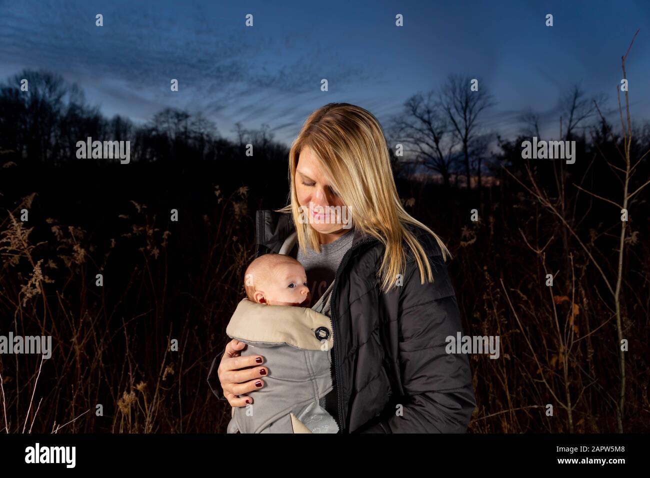 Einzelne kaukasische Mut-Wanderungen Mit Ihrem Neugeborenen Kind, Das An seinem Brustkorb An EINEM modrigen Herbsttag Befestigt ist Stockfoto