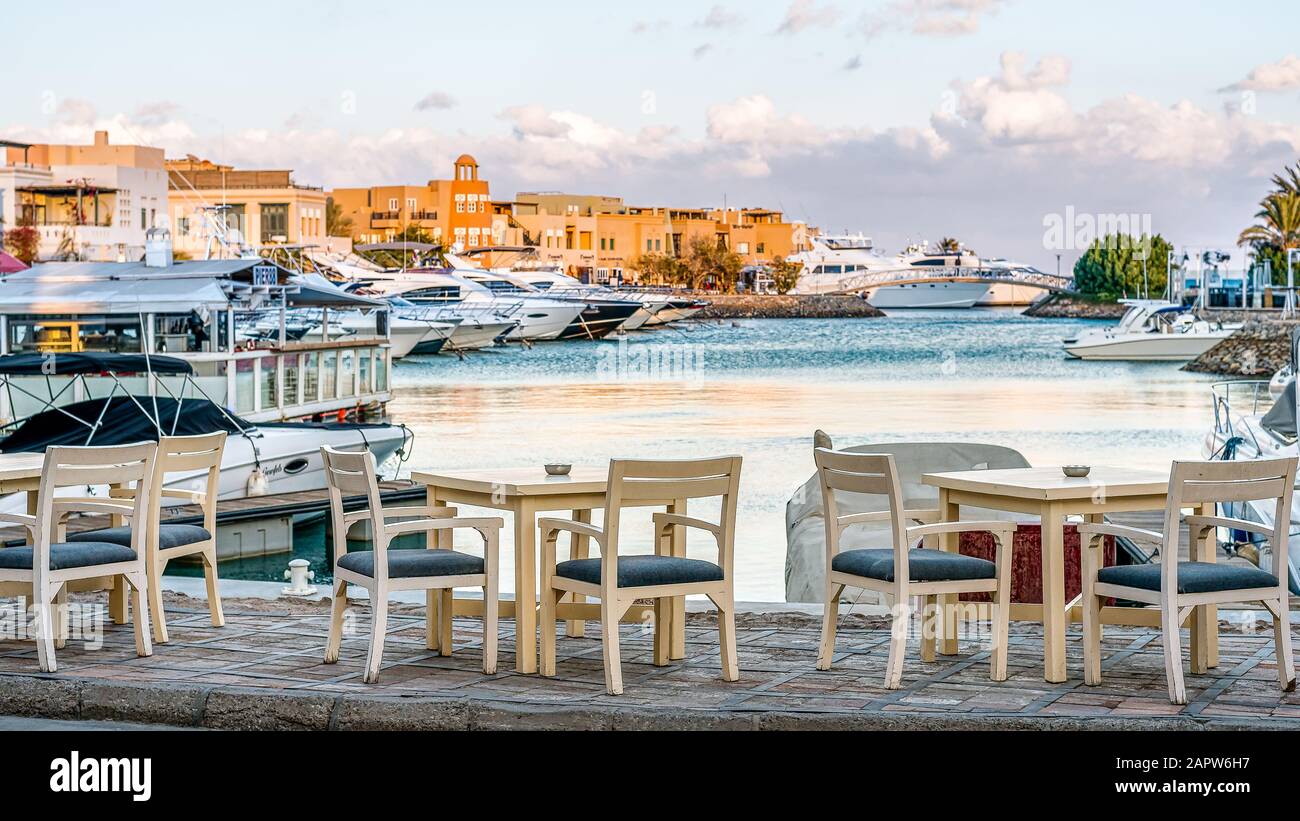 Tische und Stühle vor dem Wasser im Jachthafen mit vielen Luxusyachten, el Gouna, Ägypten, 11. Januar 2020 Stockfoto