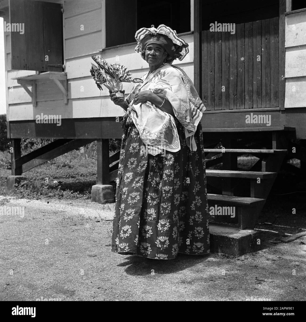Reise nach Suriname und die niederländischen Antillen Kotomisi Pauline vor dem Regierungshaus in New Nickerie in rot, weiß, blau gekleidet und mit Porträts von Königin Wilhelmina, Prinzessin Juliana und Prinz Bernhard Annotation: Pauline war die Hostess des Regierungshauses in New Nickerie Date: Oktober 1947 Ort: Nickerie, Suriname Schlüsselwörter: Kreolen, Ureinwohner, Kleidung, Frauen Stockfoto