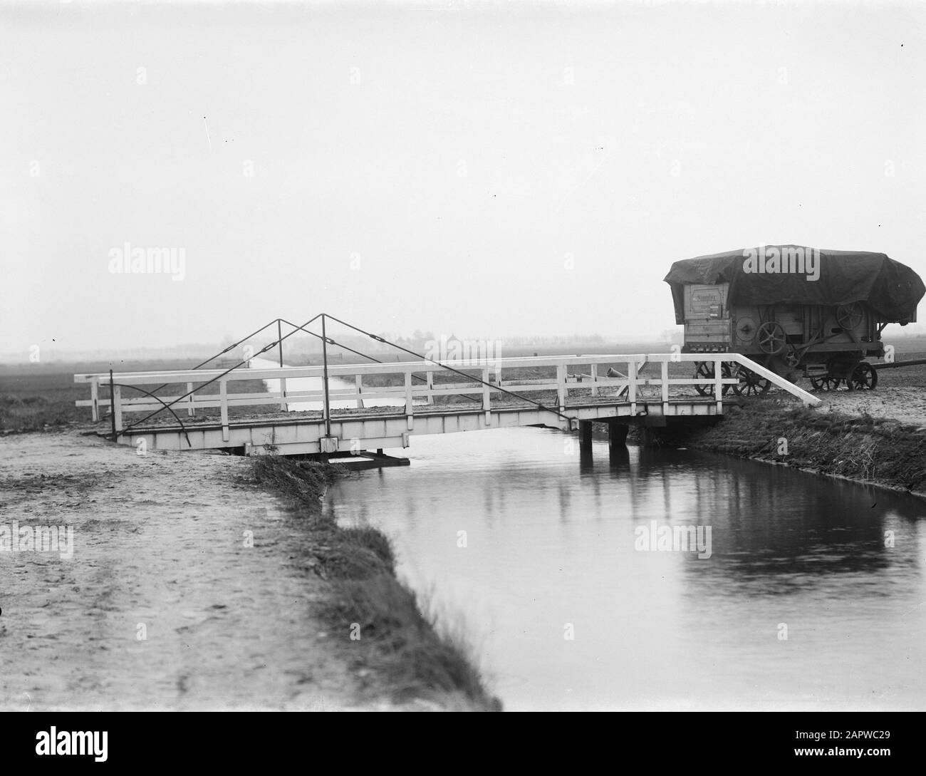 Drehbrücke mit Dreschmaschine Anmerkung: Het Zeijerveld ist eine Fläche von 620 Hektar, die sich auf der Nordwestseite von Assen in der Provinz Drenthe (Niederlande) befindet. Sie wurde 1907 von den Zeijer Landwirten von Jacob Theoor Cremer, präsident der Nederlandschen Handel-Maatschappij und ehemaliger Minister für Kolonien als wildes Land gekauft. Cremer ließ das Gebiet in den Jahren vor dem Ersten Weltkrieg von der Nederlandschen Heidemaatschappij abbauen. Vom Drentsche Hoofdvaart aus wurde der Asserwijk zur Entwässerung und zum Transport gegraben. Entlang und in der Nähe des Asserwijk ließ Cremer 15 Bauernhöfe mit einem n errichten Stockfoto