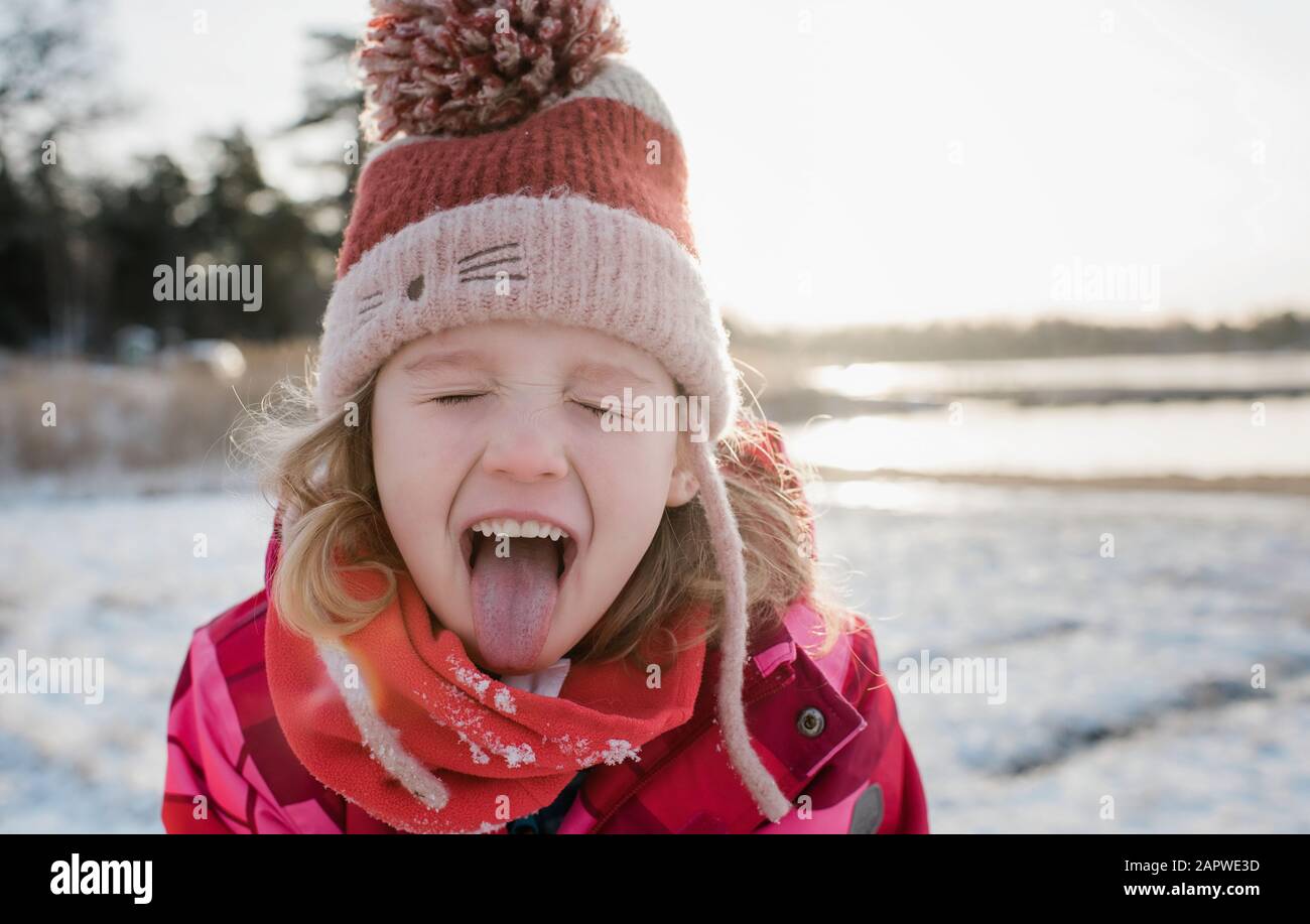 Junges Mädchen fangen Schnee mit ihrer Zunge heraus, während draußen spielen Stockfoto