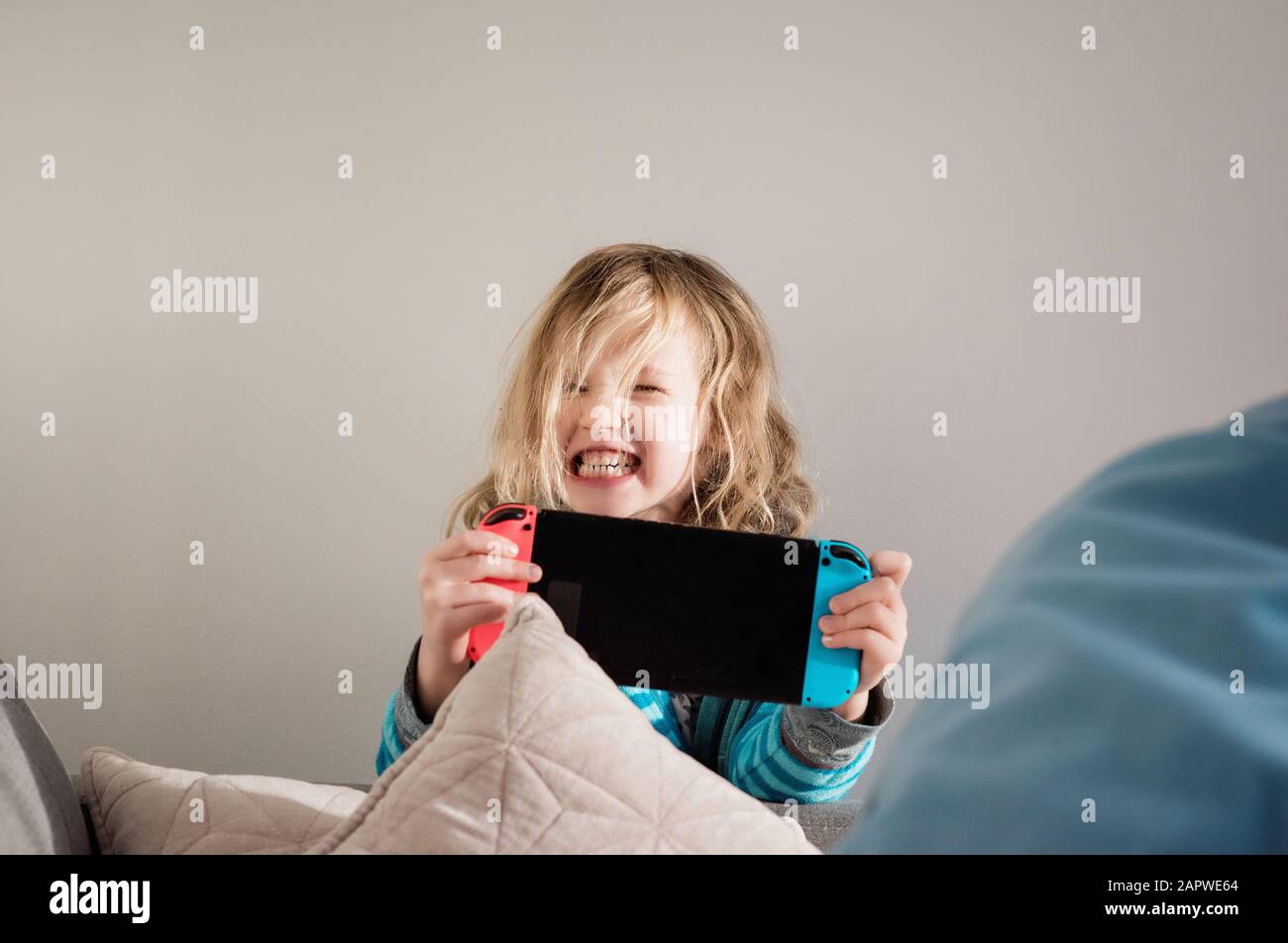 Junges Mädchen zieht Gesichter, während Nintendo-Schalter zu Hause spielen Stockfoto