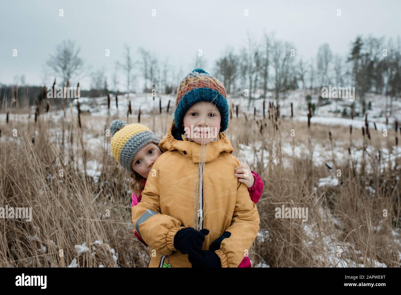 Geschwister, die im Schnee draußen spielen und die Kamera betrachten Stockfoto