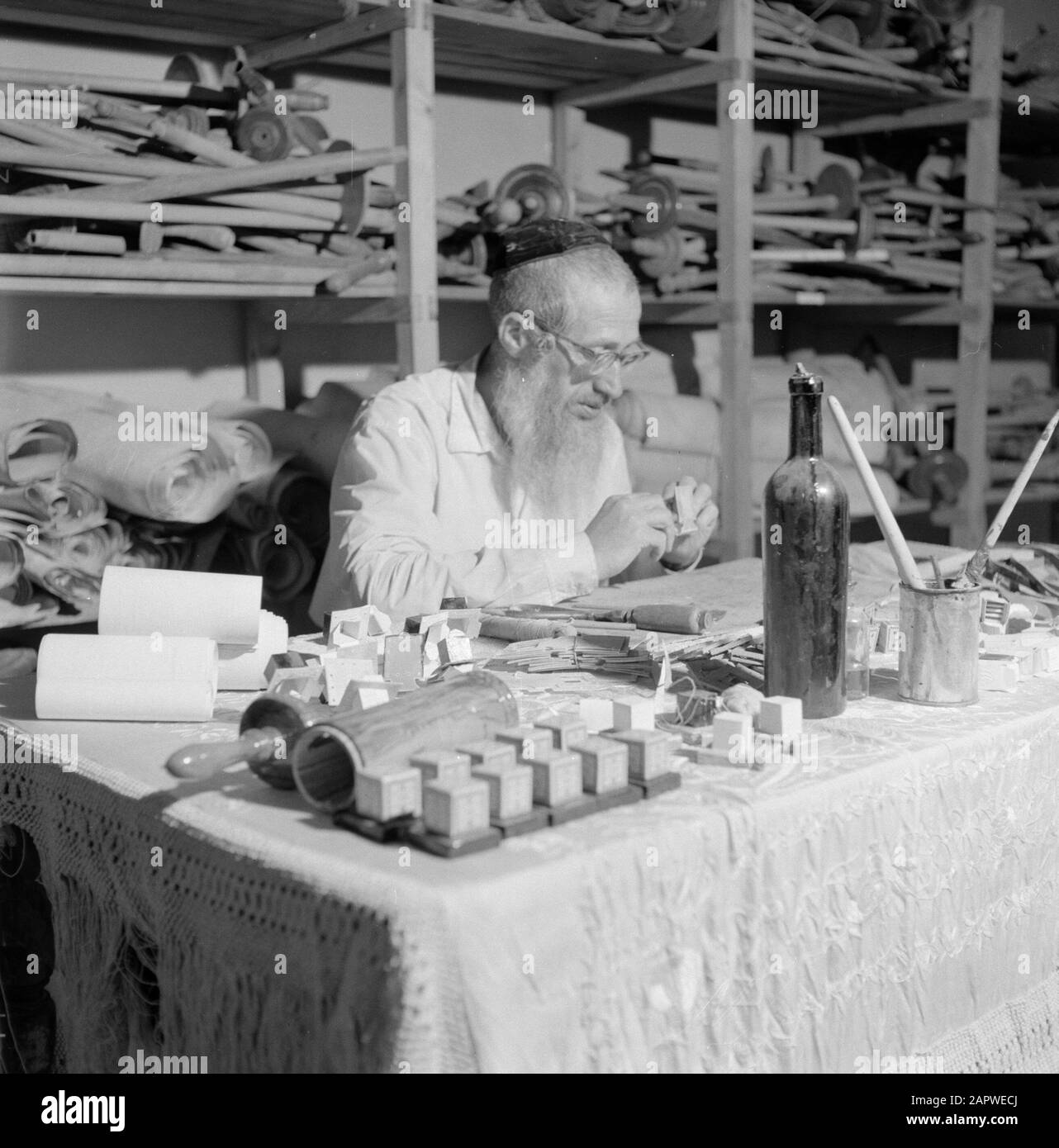 Israel 1964-1965: Jerusalem (Jerusalem), Thorarrolls Man macht thora Rollen hinter einem vollen Arbeitstisch Anmerkung: Die Tora (das Mosaische Gesetz) ist auf einer Rolle geschrieben, die von der Haut eines koscheren Tieres aus Pergament gefertigt wurde. Die verschiedenen Teile von Pergament sind mit einer Sehne aneinander befestigt, der Text wird handschriftlich geschrieben. Die Tinte wird oft von selbst hergestellt und muss bestimmte Anforderungen erfüllen. Schließlich ist die Rolle an zwei Holzstöcken mit Griffen befestigt und beide Enden werden gegen das mittlere Datum gerollt: 1964 Ort: Israel, Jerusalem Schlüsselwörter: Thorarol, Werkzeuge, Handarbeit, jüdische Religion Stockfoto