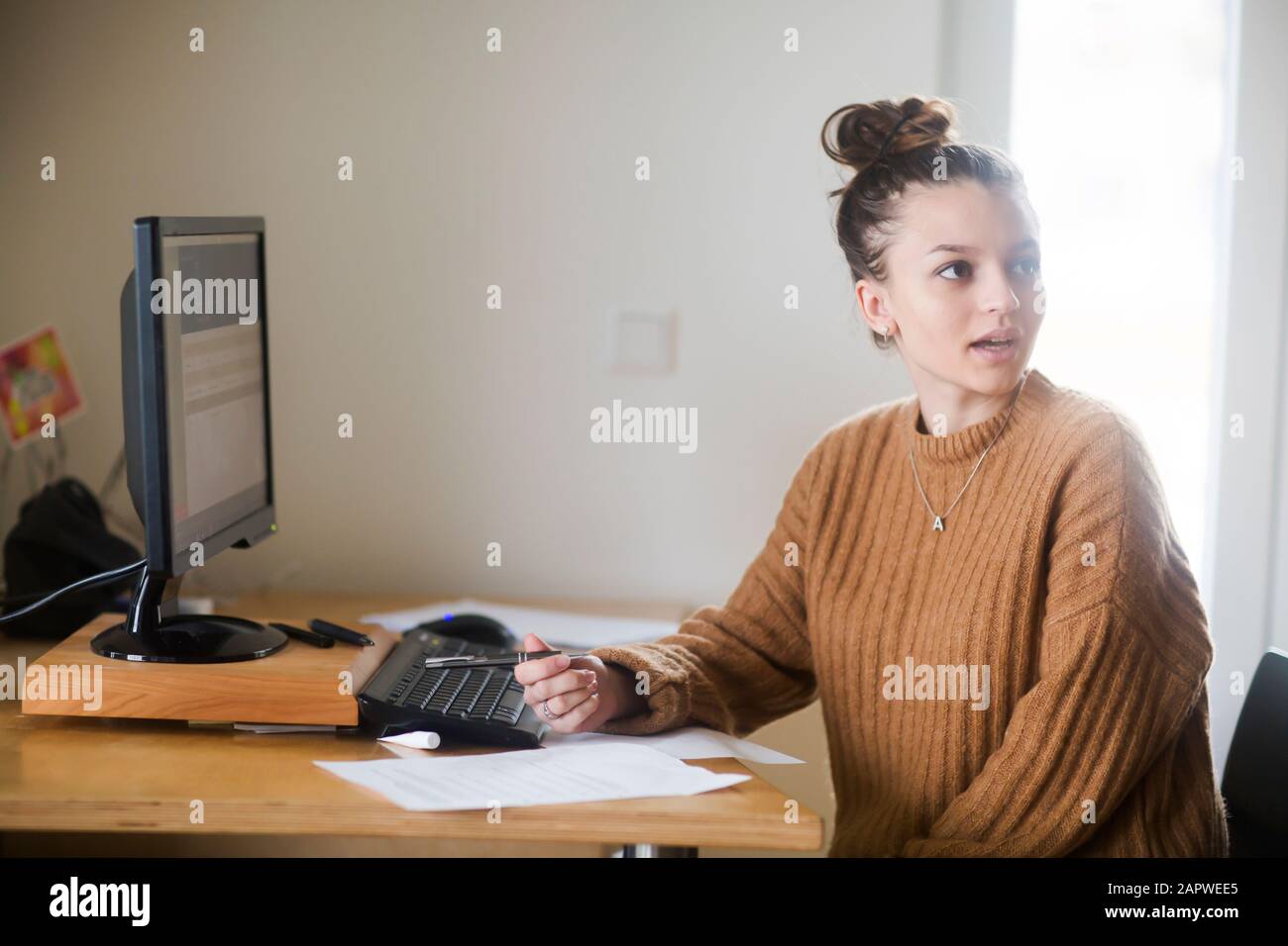 Junge Frau mit Brötchen im Büro Stockfoto