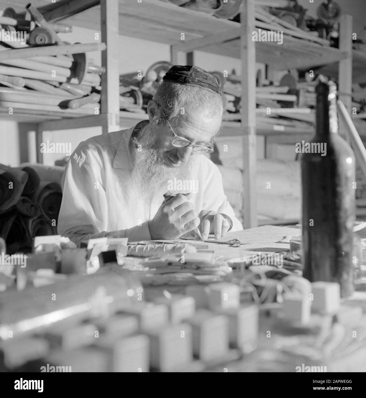 Israel 1964-1965: Jerusalem (Jerusalem), Thorarrolls Man macht thora Rollen hinter einem vollen Arbeitstisch Anmerkung: Die Tora (das Mosaische Gesetz) ist auf einer Rolle geschrieben, die von der Haut eines koscheren Tieres aus Pergament gefertigt wurde. Die verschiedenen Teile von Pergament sind mit einer Sehne aneinander befestigt, der Text wird handschriftlich geschrieben. Die Tinte wird oft von selbst hergestellt und muss bestimmte Anforderungen erfüllen. Schließlich ist die Rolle an zwei Holzstöcken mit Griffen befestigt und beide Enden werden gegen das mittlere Datum gerollt: 1964 Ort: Israel, Jerusalem Schlüsselwörter: Thorarol, Werkzeuge, Handarbeit, jüdische Religion Stockfoto