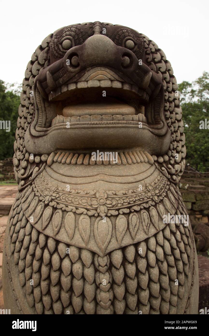 Statue aus Stein eines Löwen mit einem weißen Himmel und Bäumen dahinter Stockfoto