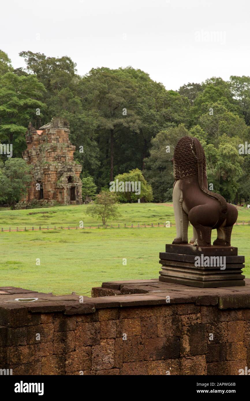 Statue eines Löwen gegenüber alten Tempel und grünen Feld, Siem Reap Stockfoto