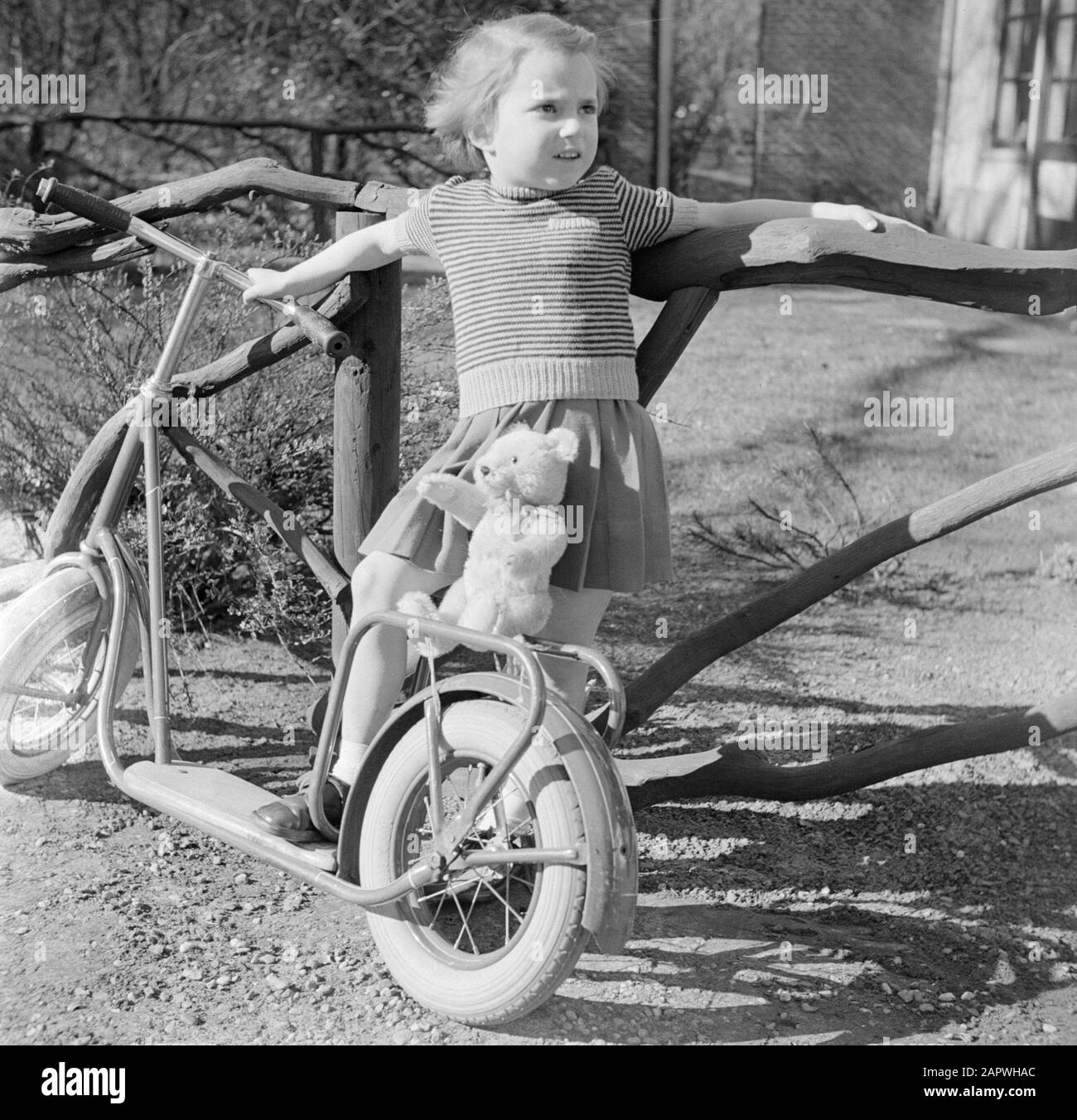 Modefotografie Mädchen mit Autoped und Teddybär Datum: 1952 Schlagwörter: Autopeds, Kleidung, Mädchen Stockfoto
