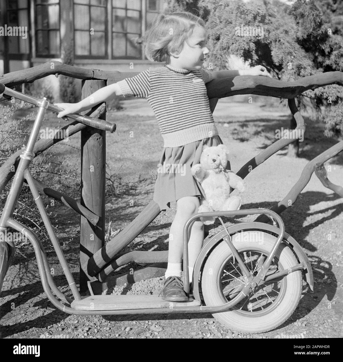 Modefotografie Mädchen mit Autoped und Teddybär Datum: 1952 Schlagwörter: Autopeds, Kleidung, Mädchen Stockfoto