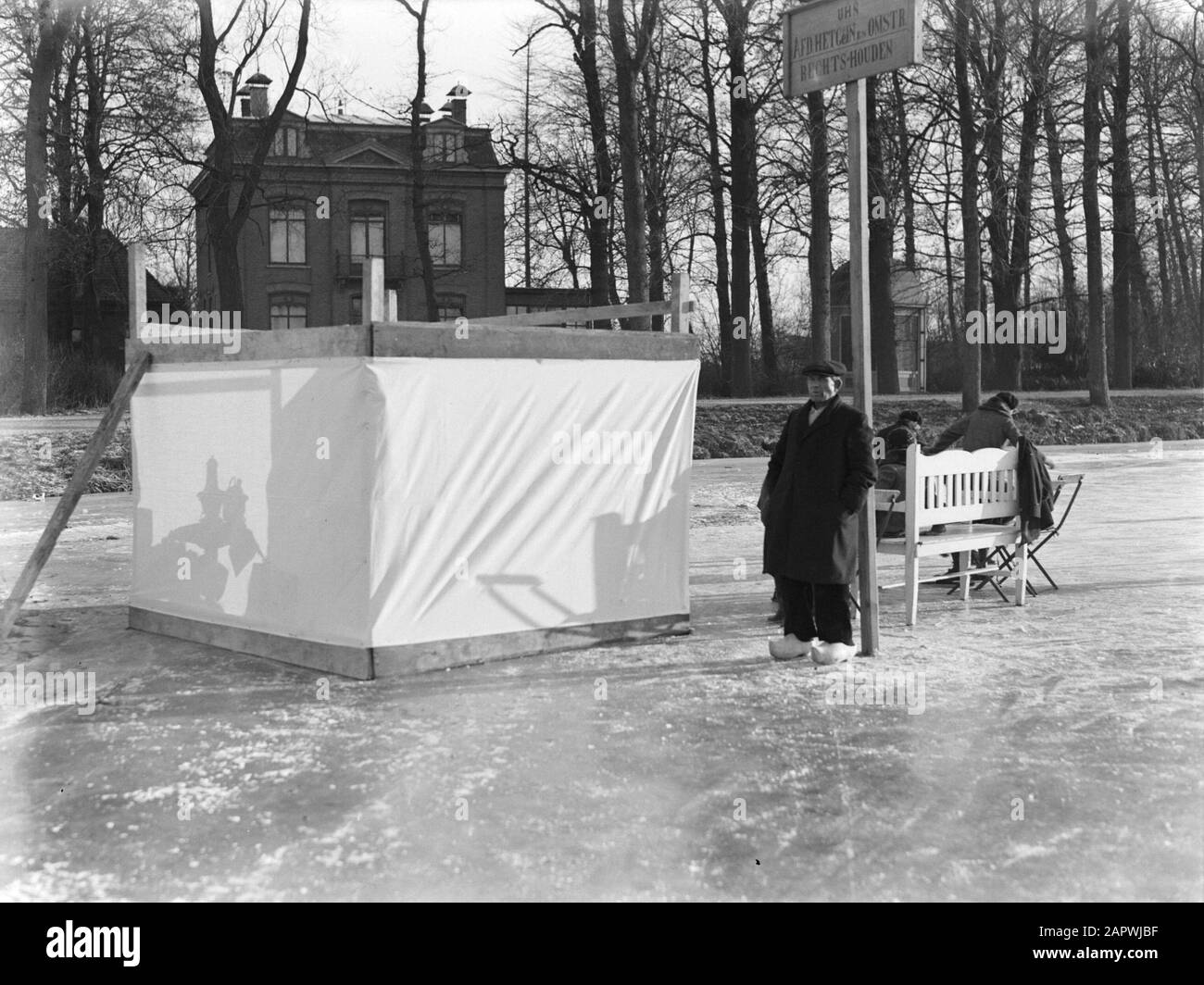 Eisspieß auf den gefrorenen Gewässern in den Niederlanden Menschen an einem Plätzchen und Zopie mit einer Bank und Stühlen auf dem fördernde Wasser des Gein Datum: 1931 Ort: Gein, Noord-Holland Schlüsselwörter: Eis, Winter Stockfoto