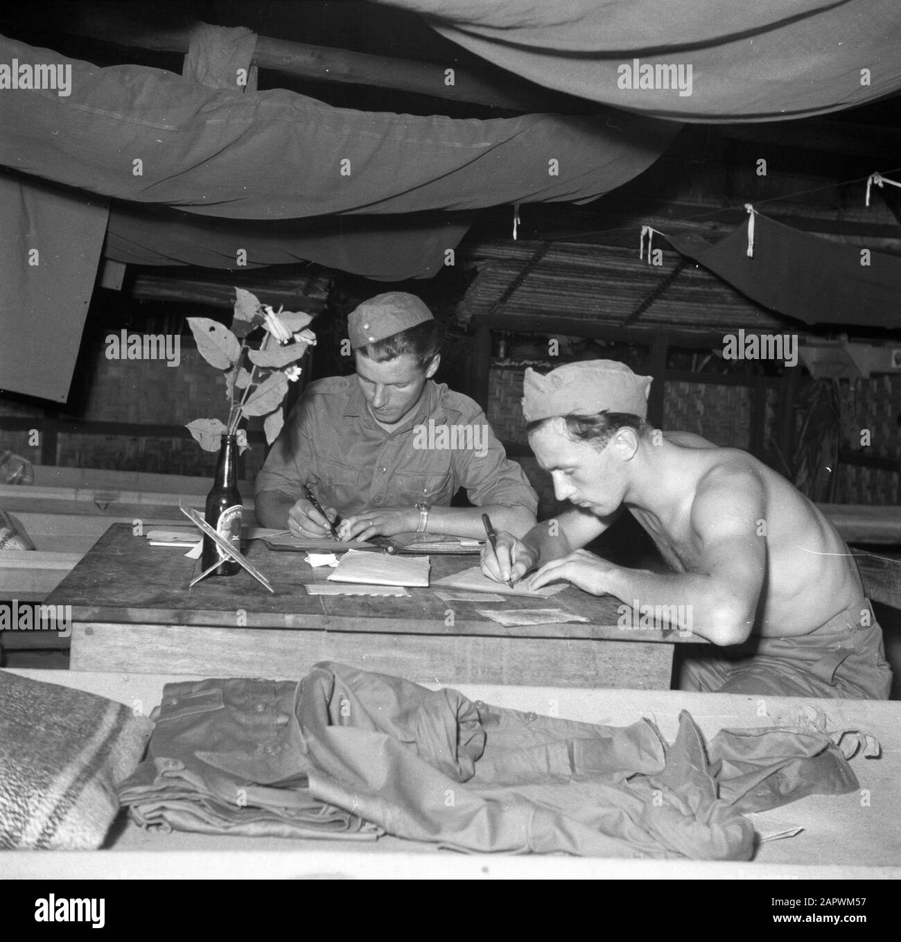 Reisen nach Suriname und die niederländischen Antillen Soldaten schreiben Briefe in ihr Lager bei Zanderij in Suriname. Auf dem Tisch eine Filiale mit Blumen in einer Bierflasche Datum: 1947 Ort: Suriname, Zanderij Schlüsselwörter: Bier, Briefe, Militär Stockfoto