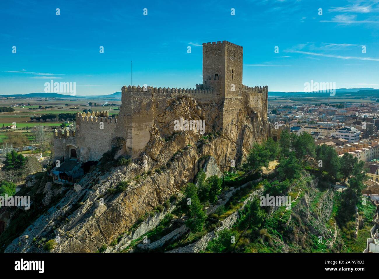 Luftaufnahme der mittelalterlichen Burg Almansa mit Donjon und Innenhof auf einem Felsen, der von dem von einem runden Ring aus roten Dachhäusern umgebenen Plateau auftaucht Stockfoto