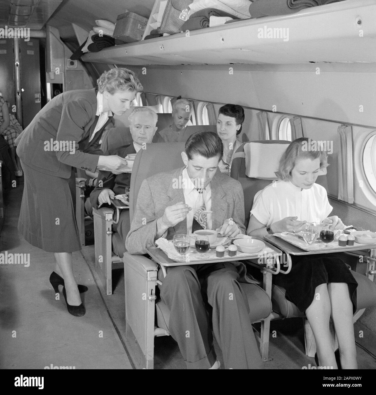 Werbung für KLM-Passagiere bei der Mahlzeit in einem KLM-Flugzeug Datum: 1950 Standort: Schiphol Schlüsselwörter: Mahlzeiten, Reisende, Flugzeuge, Flugzeugpersonal Stockfoto