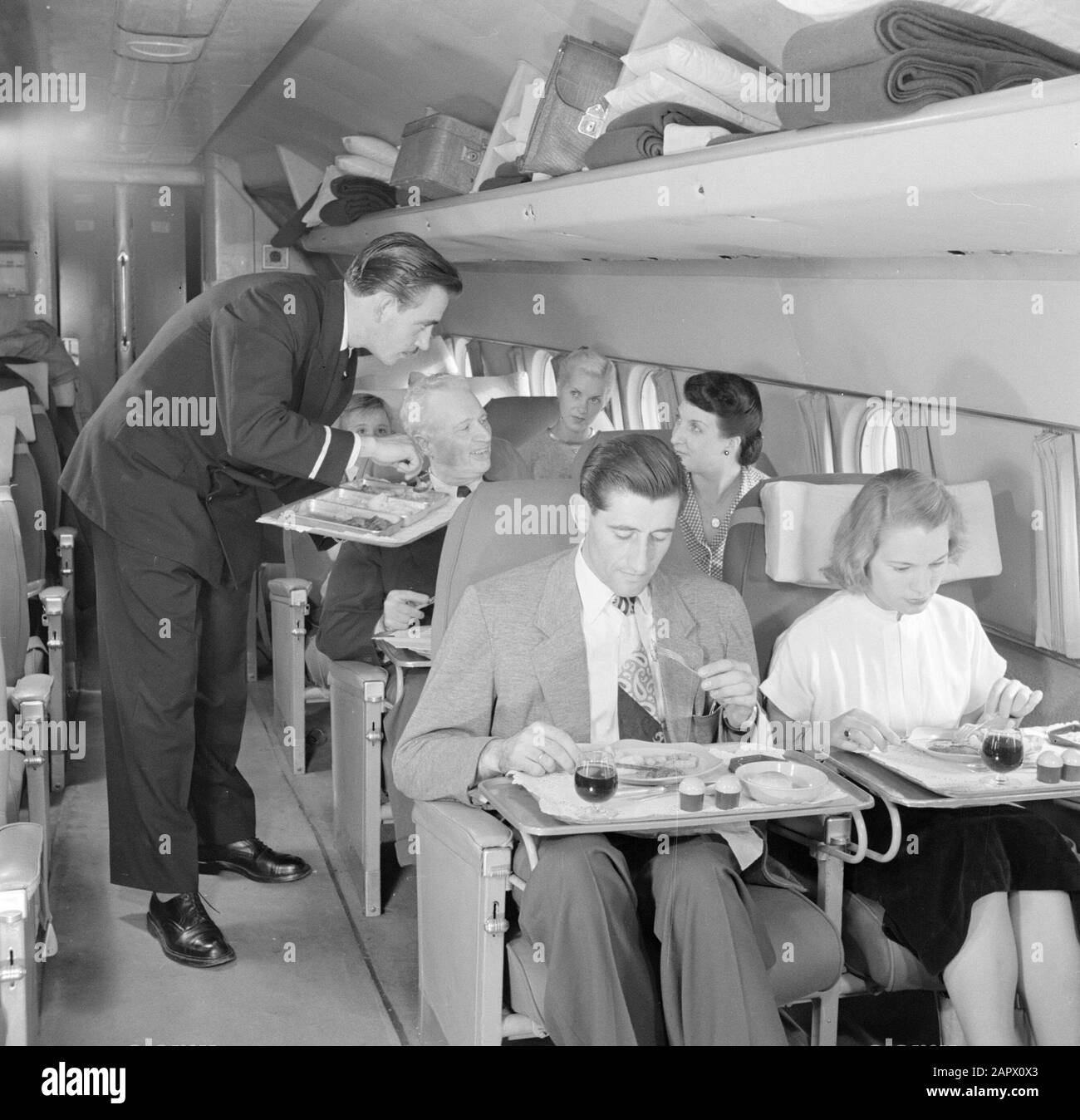 Werbung für KLM-Passagiere bei der Mahlzeit in einem KLM-Flugzeug Datum: 1950 Standort: Schiphol Schlüsselwörter: Mahlzeiten, Reisende, Flugzeuge, Flugzeugpersonal Stockfoto