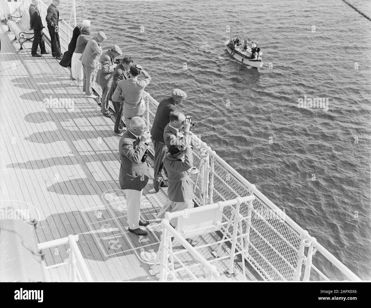 Seefahrt mit Frau Johan van Oldenbarnevelt nach Norwegen Passagiere auf dem Geländer, wenn sie sich einem Boot nähern. Mit dem Zuschauer Mr. Delprat, hinter ihm der Politiker Charles Welter Datum: 1933 Ort: Norwegen Schlagwörter: Kreuzfahrten, Kreuzfahrtschiffe, Zäune, Spaß, Politiker, Reisende, Schiffe, Boote, Tourismus, Ferngläser persönlicher Name: Delprat, D.A., Welter, Kap Stockfoto