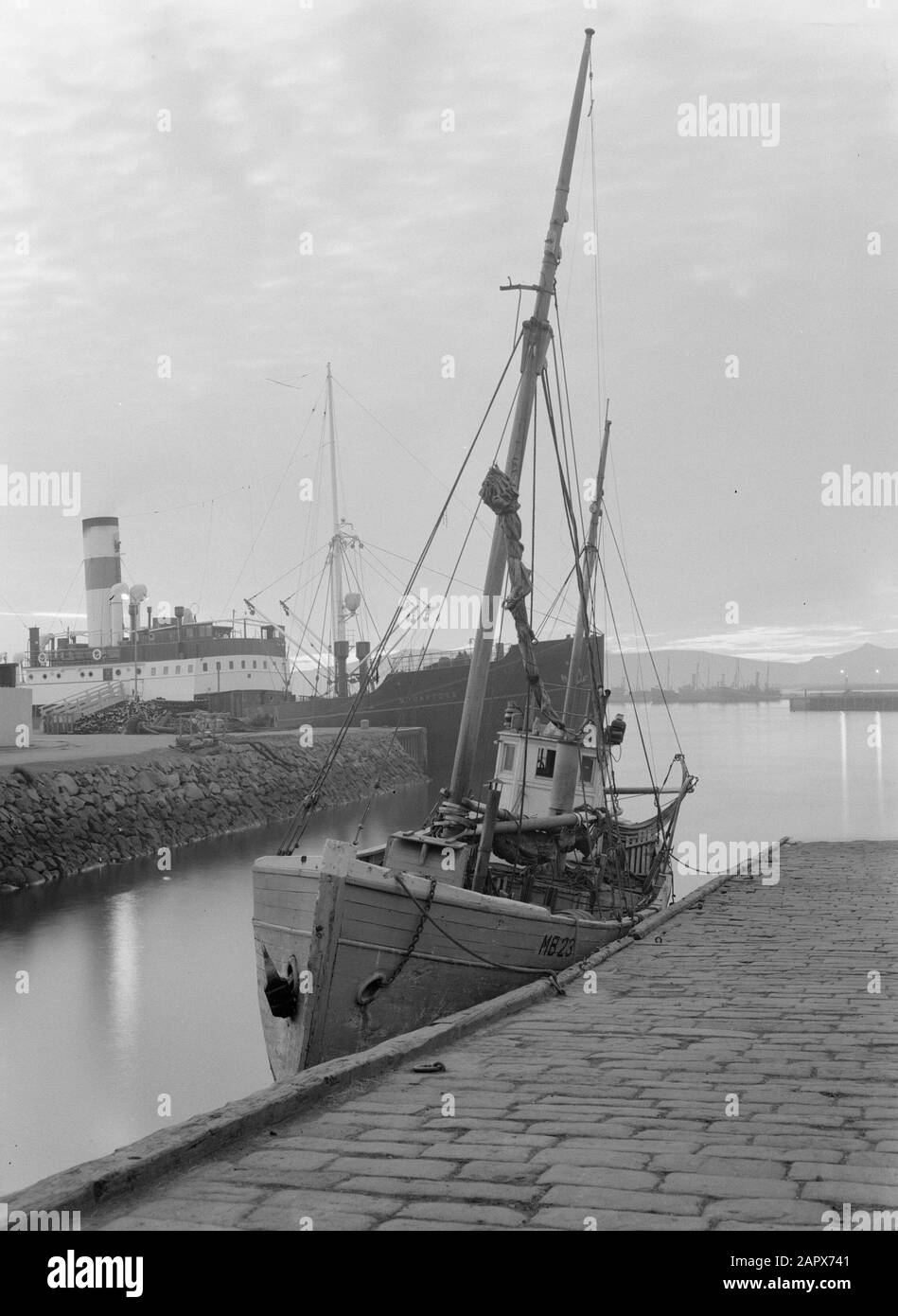 Island Reykjavik, Hafenblick: Fischerboot MB 23 und im Hintergrund das Frachtschiff Bruarfoss Datum: 1934 Standort: Island, Reykjavik Schlüsselwörter: Häfen, Kais, Schiffe, Fischereischiffe Stockfoto