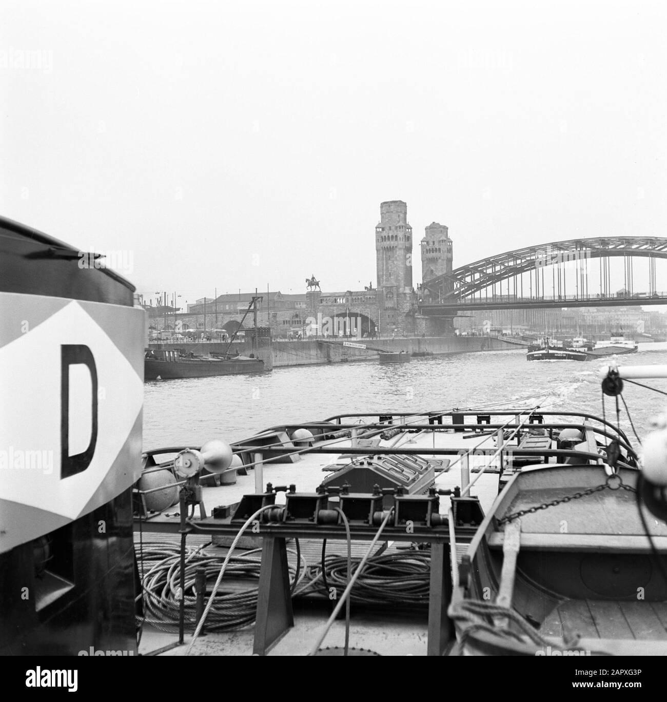 Rheinnavigation, Bericht vom Schlepper Damco 9: Westdeutschland Drag den Damco 135 unter die Rheinbrücke bei Köln Datum: 1. April 1955 Standort: Deutschland, Köln, Westdeutschland Schlagwörter: Flüsse, Schlepper, Eisenbahnbrücken, Stadtansichten, Türme Stockfoto
