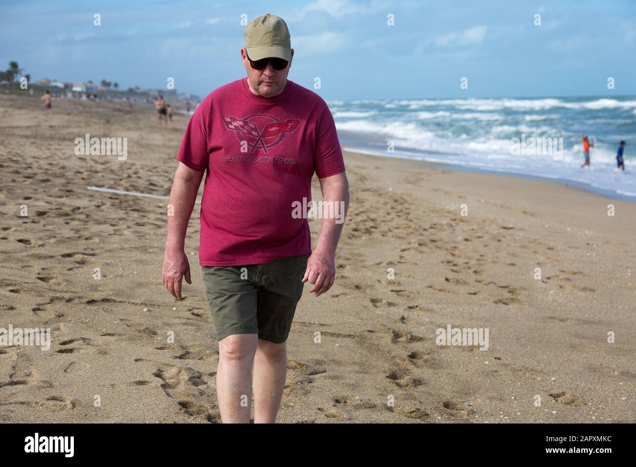 Ein Beachcomber mit einem roten Corvette T-Shirt und grünen Shorts sucht nach Schätzen, während er Stuart Beach auf Hutchinson Island, Florida, USA, spaziert. Stockfoto