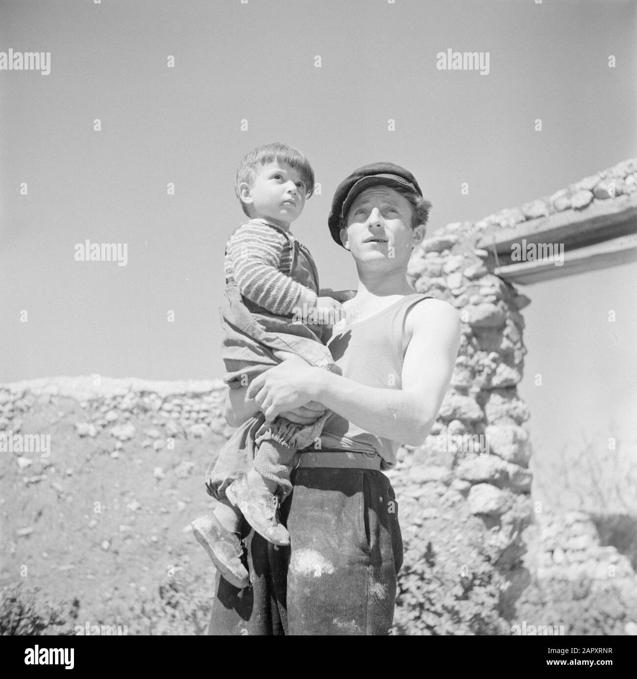 Israel 1948-1949 Vater mit Kind auf Arm an dem Ort, an dem die Familie ihr Haus bauen wird. Dieser Auswanderer trägt am Unterarm die Lagernummer aus dem Konzentrationslager Auschwitz. Israel gibt diesen Kriegsopfern neue Lebensperspektive Datum: 1948 Ort: Auschwitz, Israel Schlüsselwörter: Konzentrationslager, Emigranten, Kinder, Kriegsopfer Stockfoto