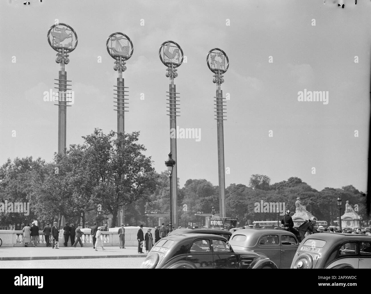 Weltausstellung Paris 1937 Vier Pole mit Symbolen in der Nähe der französischen Pavillons, mit öffentlichem, Autoverkehr, einschließlich eines fahrenden Autos, und einem Polizisten zu Pferd Datum: 1937 Ort: Frankreich, Paris Schlagwörter: Autos, Pferde, Polizisten, Öffentlichkeit, Straßenbilder, Symbole, Uniformen, Verkehrsmittel, Weltausstellungen Stockfoto