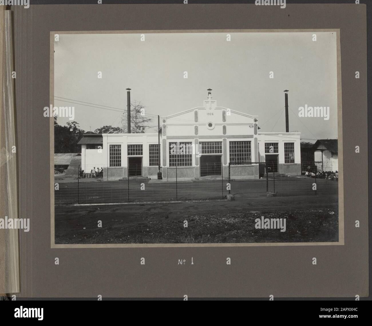 Fotoalbum Deli Maatschappij: Kaffeefabrik Alas Tledek, nach 1926 Vorderansicht der Fabrik. Die große Tür bietet Zugang zum Maschinenraum, zur Tür links zur Trockenvorbereitung und zur Tür rechts zur Bürobeschriftung: In der Trockenzubereitung werden die Kaffeebeeren der Kaffeepflanzen abgezippt, vom Schmutz gereinigt, indem sie die Beeren gleichwie in einer Art Sieb in die Luft werfen. In Wasser sortiert und schließlich in der Sonne oder in einer Trocknungsmaschine getrocknet. Datum: 1926 Standort: Indonesien, Java, Niederländische Ostindien Schlüsselwörter: Fabriken, Kaffee Stockfoto