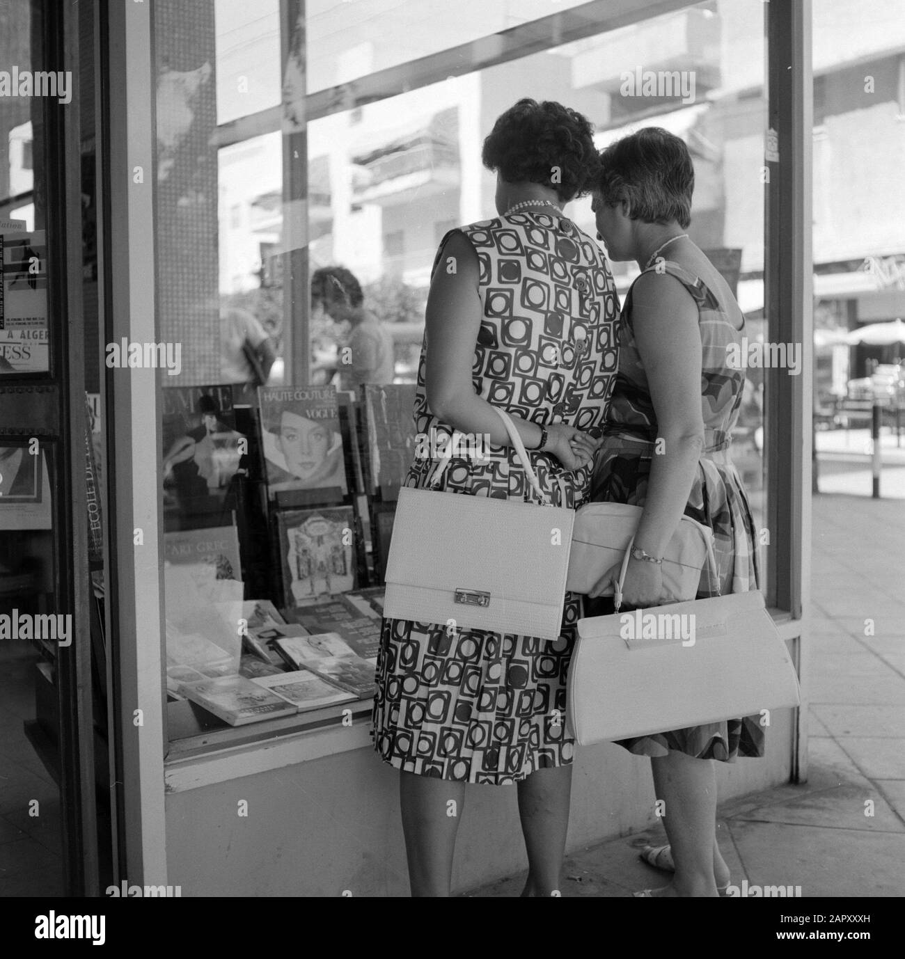 Israel 1964-1965: Tel Aviv, Buchladen Passanten schauen interessiert in das Fenster einer Buchhandlung Annotation: Die Buchhandlung verkauft ausschließlich französischsprachige Bücher. Zu Hause haben die Leute viele Bücher, sie haben ein separates Bücherregal für jedes Kind und eines für die Eltern. Datum: 1964 Standort: Israel, Tel Aviv Schlüsselwörter: Bücher, Buchhandlung, Schaufenster, Handtaschen, Straßenplastiken, Fußgänger Stockfoto