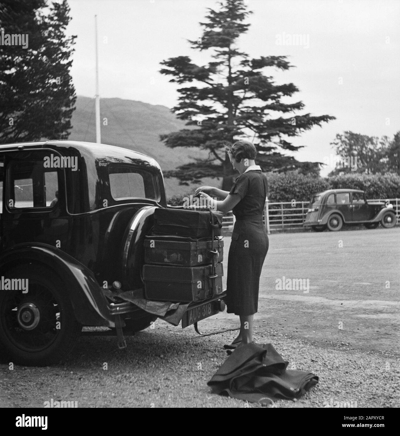 Schottland - Die Frau aus den Highlands bindet Koffer auf der Rückseite des Autos Datum: 1934 Ort: Großbritannien Schlagwörter: Autos, Gepäck, Frauen Stockfoto