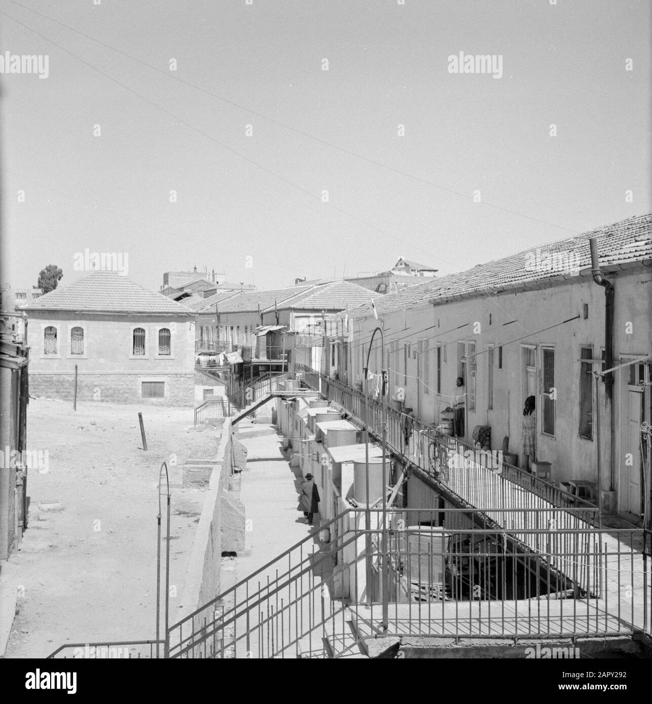 Israel 1964-1965: Jerusalem (Jerusalem), Mea Shearim Wohnhäuser auf einer Galerie, eine Reihe von Bewohnern, die außerhalb in der Türöffnung stehen Anmerkung: MEA Shearim, auch Meah Shearim oder hundert Tore genannt, ist einer der ältesten Bezirke Jerusalems. Sie wurde ab etwa 1870 von hasidischen Juden erbaut, die bis dahin in der Altstadt lebten. Es war jedoch zu wenig Platz und so kauften sie ein Stück Land nordwestlich der Stadt. Dieses Land, ein Sumpfgebiet, wurde zu Land kultiviert, um ein neues Stadtviertel zu errichten: Meah Shearim. Der Distrikt ist anno 2012 als das extremste orthodoxe Juwis bekannt Stockfoto